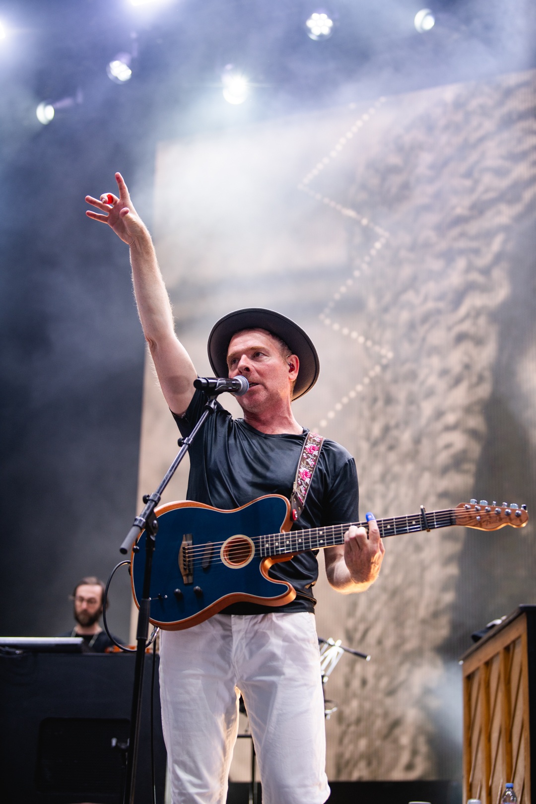 Musician in black shirt and hat playing guitar on stage
