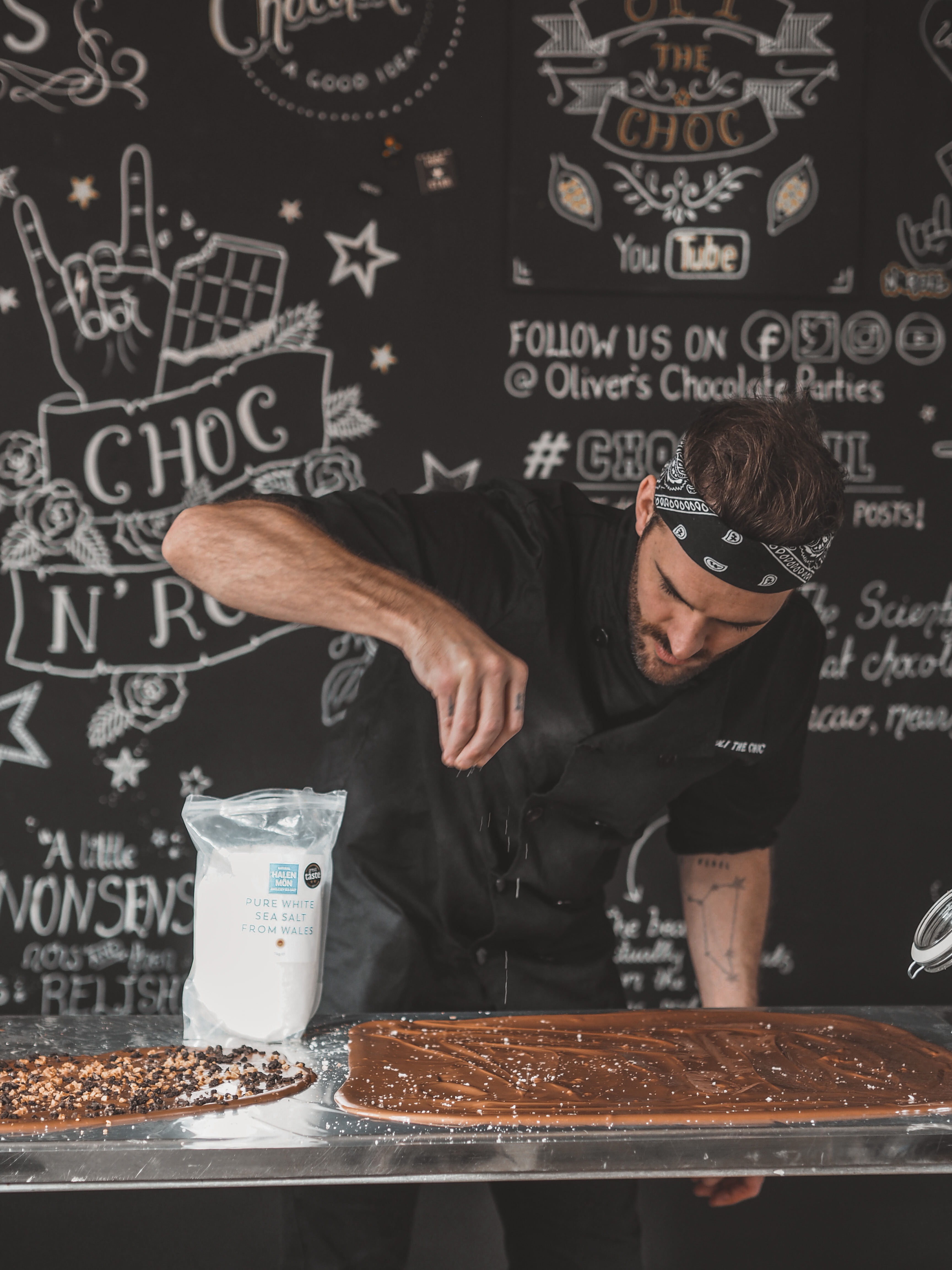 Chocolatier sprinkling salt on handmade chocolate slab