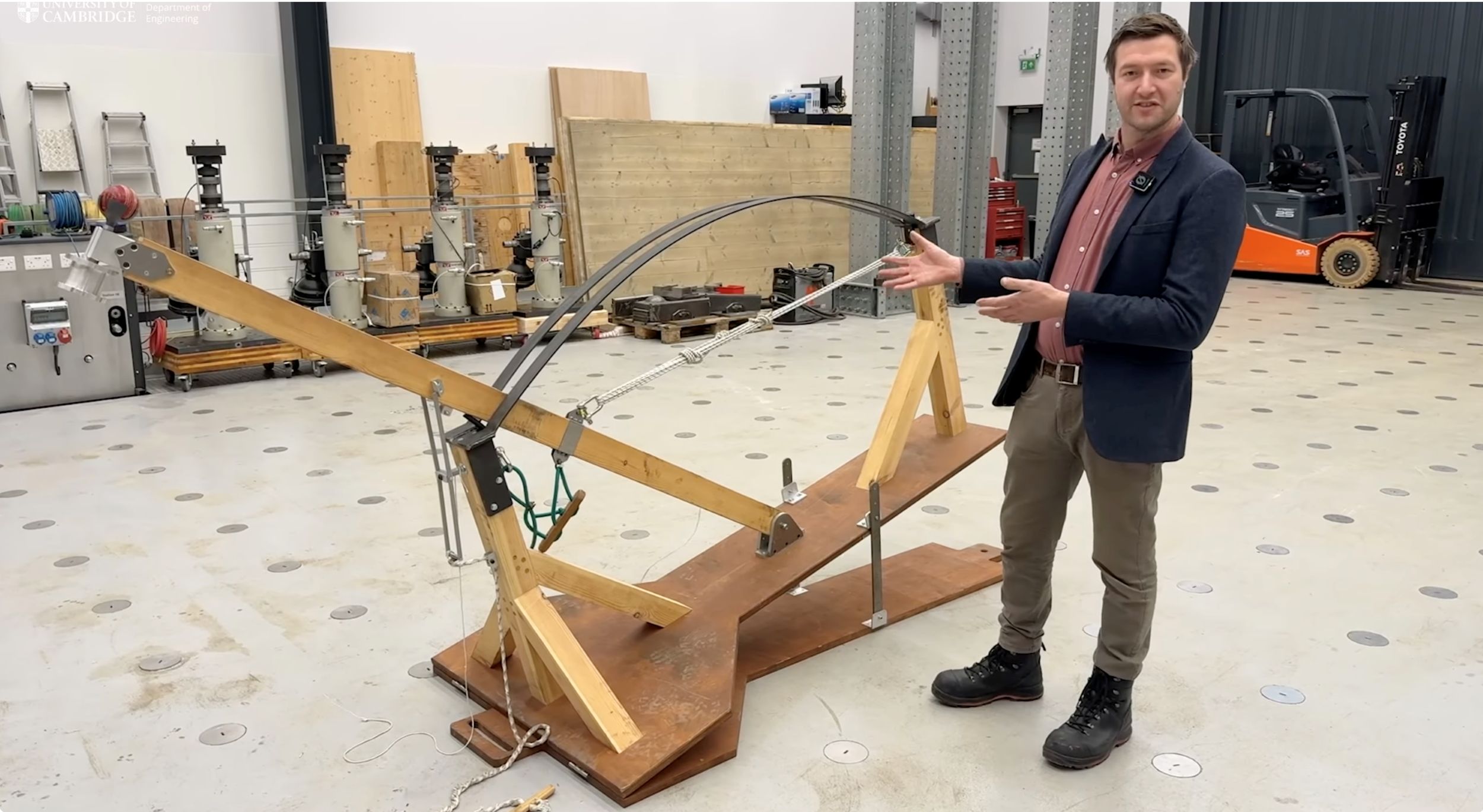 Man demonstrating medieval trebuchet model in workshop