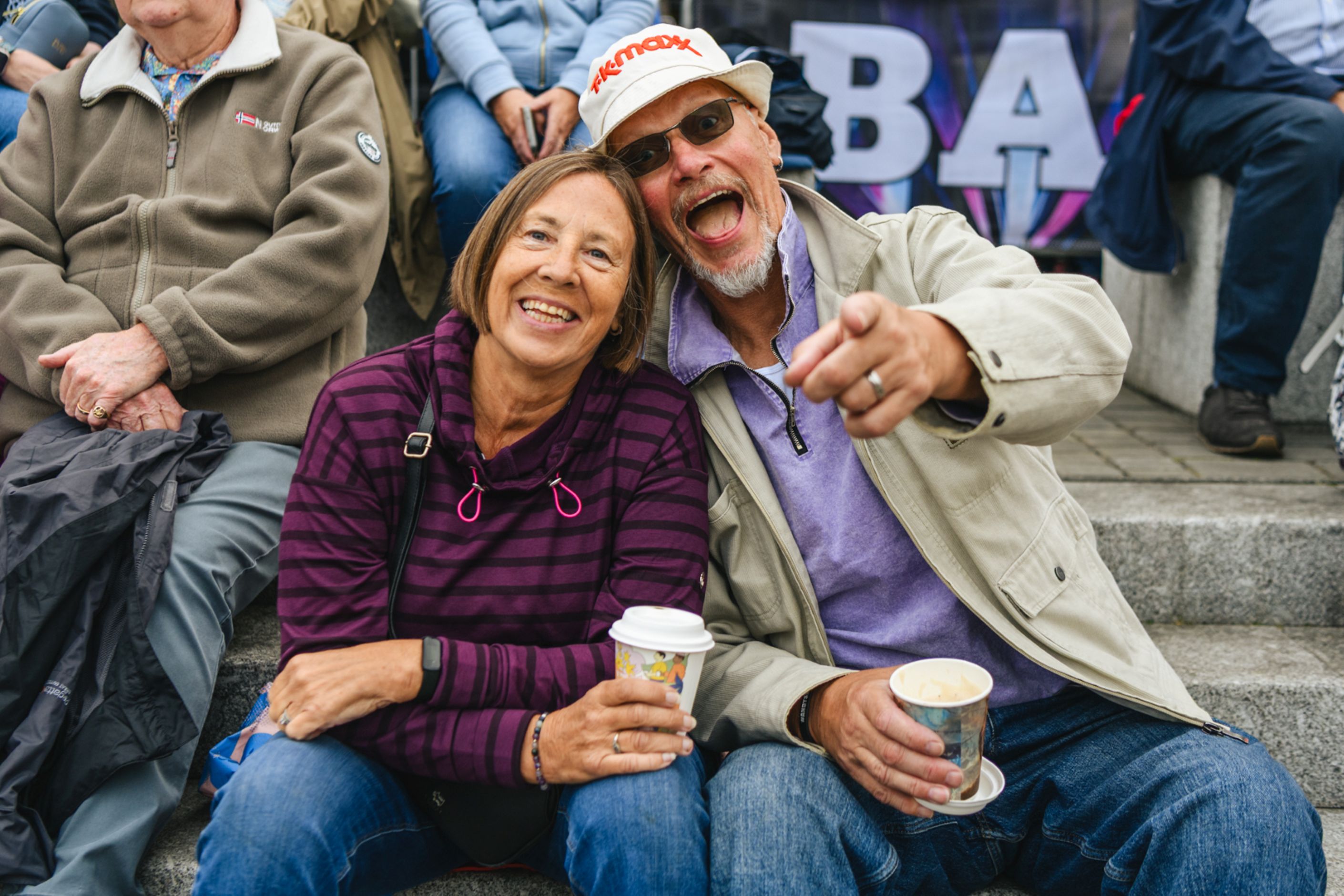 Cheerful couple sitting on steps enjoying coffee at outdoor event