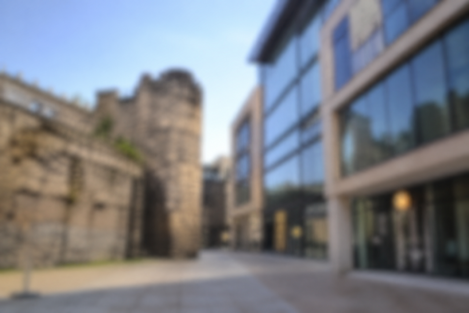 Medieval stone tower beside modern glass-fronted office building