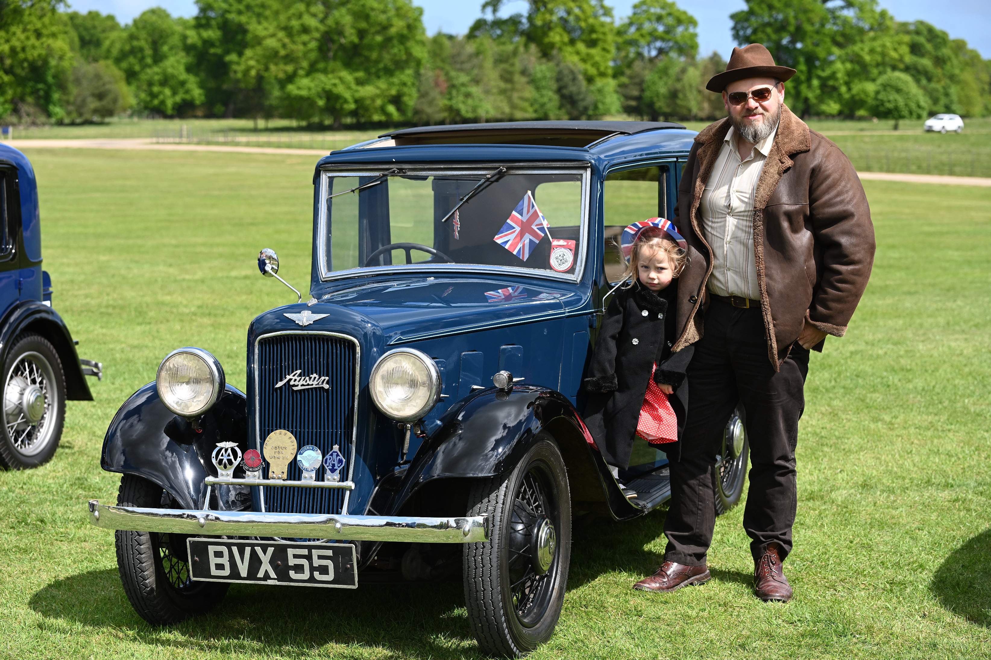 Vintage blue Austin car on grass with man and child in period attire