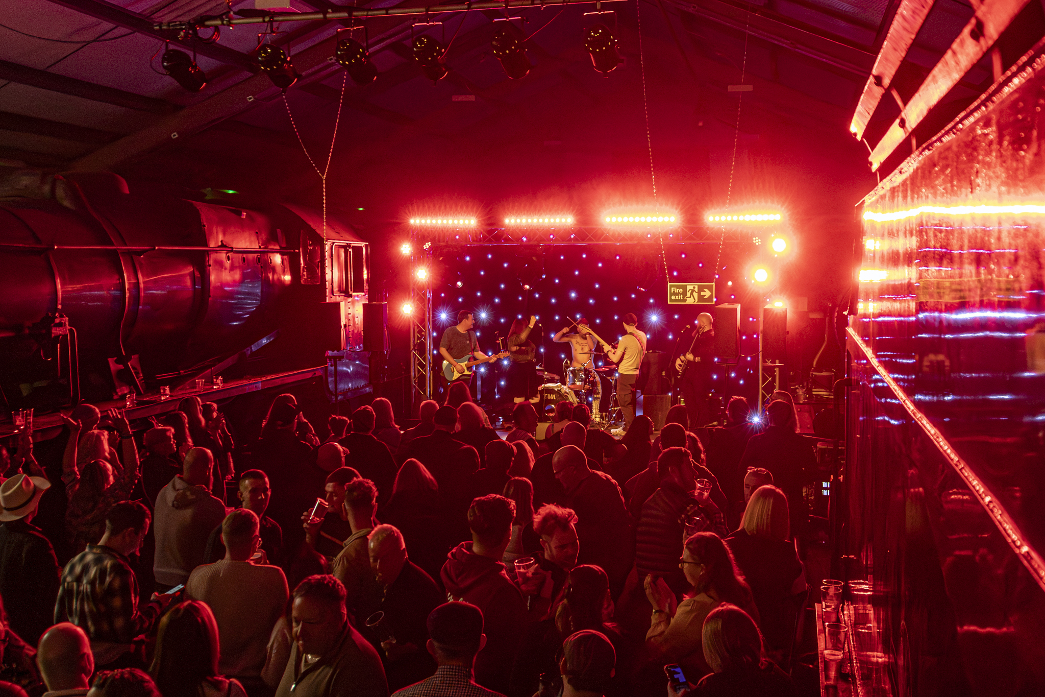 Live band performing in dimly lit venue with red lighting