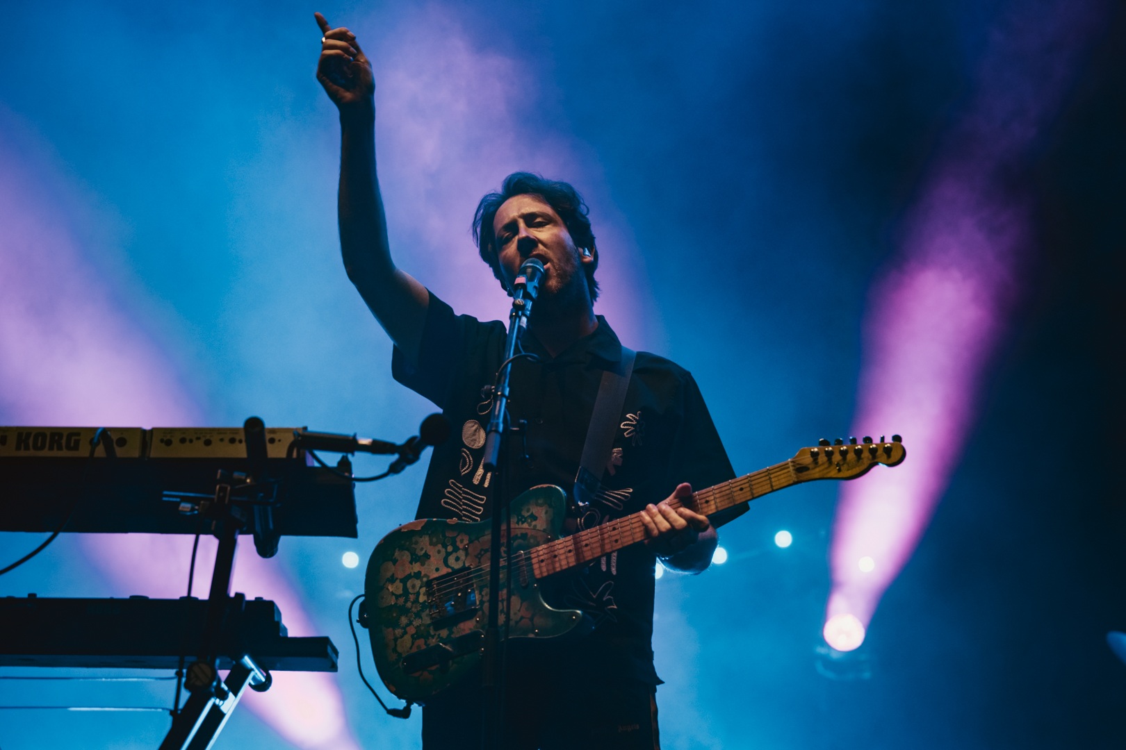 Musician playing guitar on stage with colourful lights
