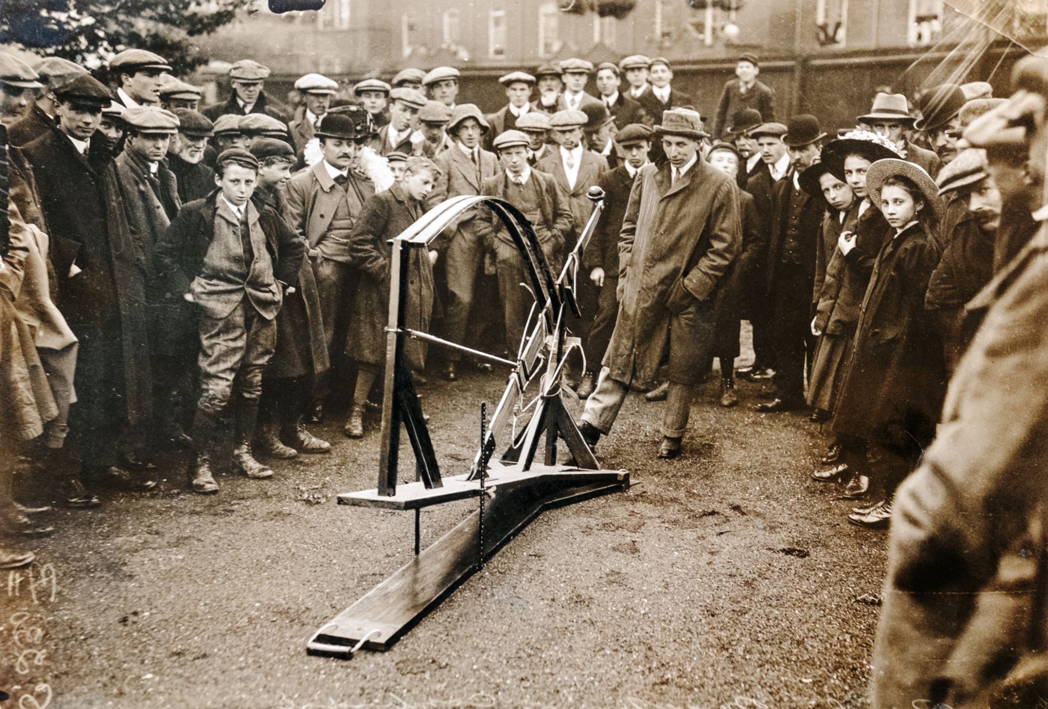 Historical group observing a mechanical device outdoors