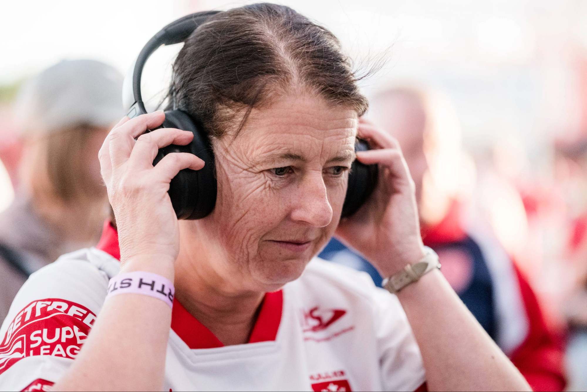 Woman in white sports jersey adjusting black headphones
