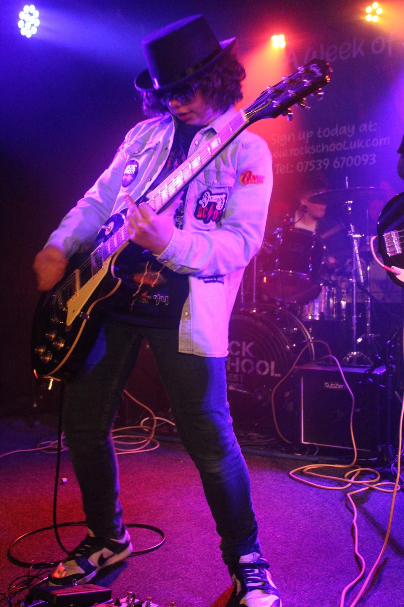Guitarist in blue jacket and hat performing on stage