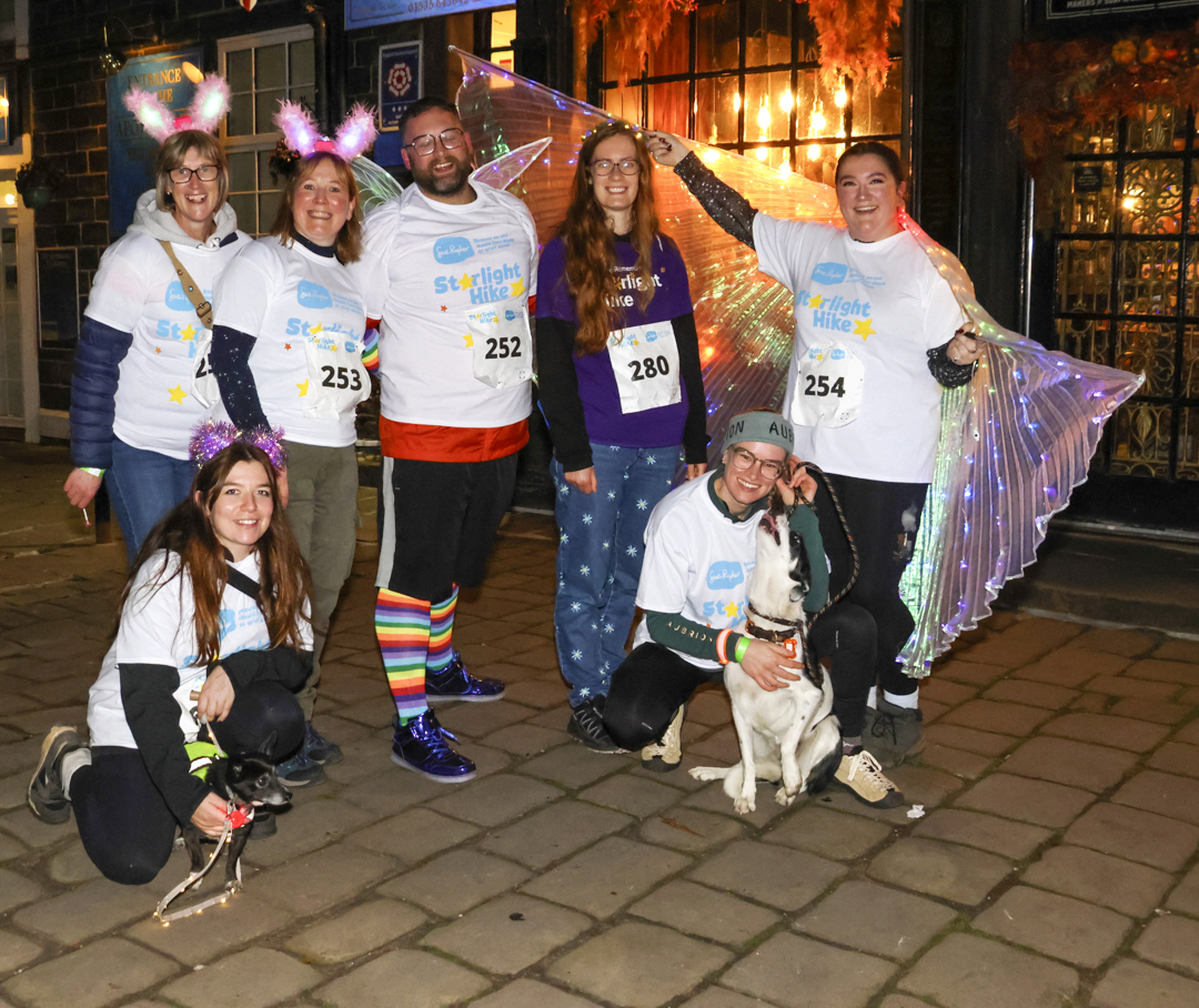 Group of people in colourful outfits and fairy lights on cobblestone street