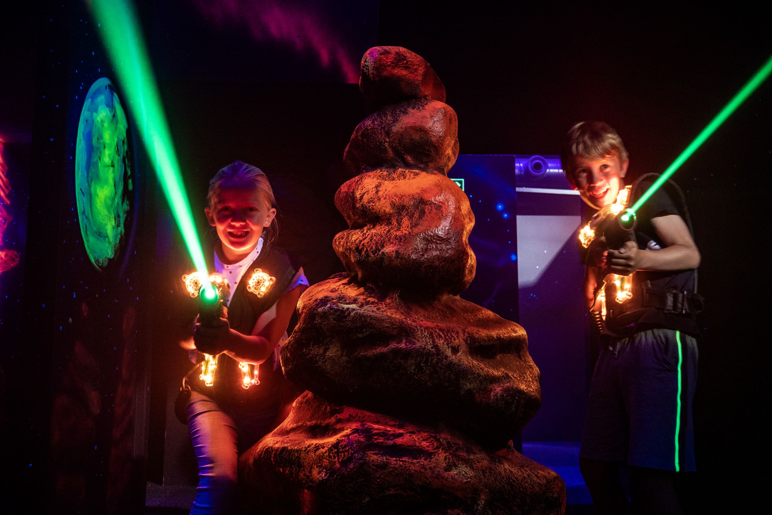Children playing laser tag in a dark, neon-lit arena