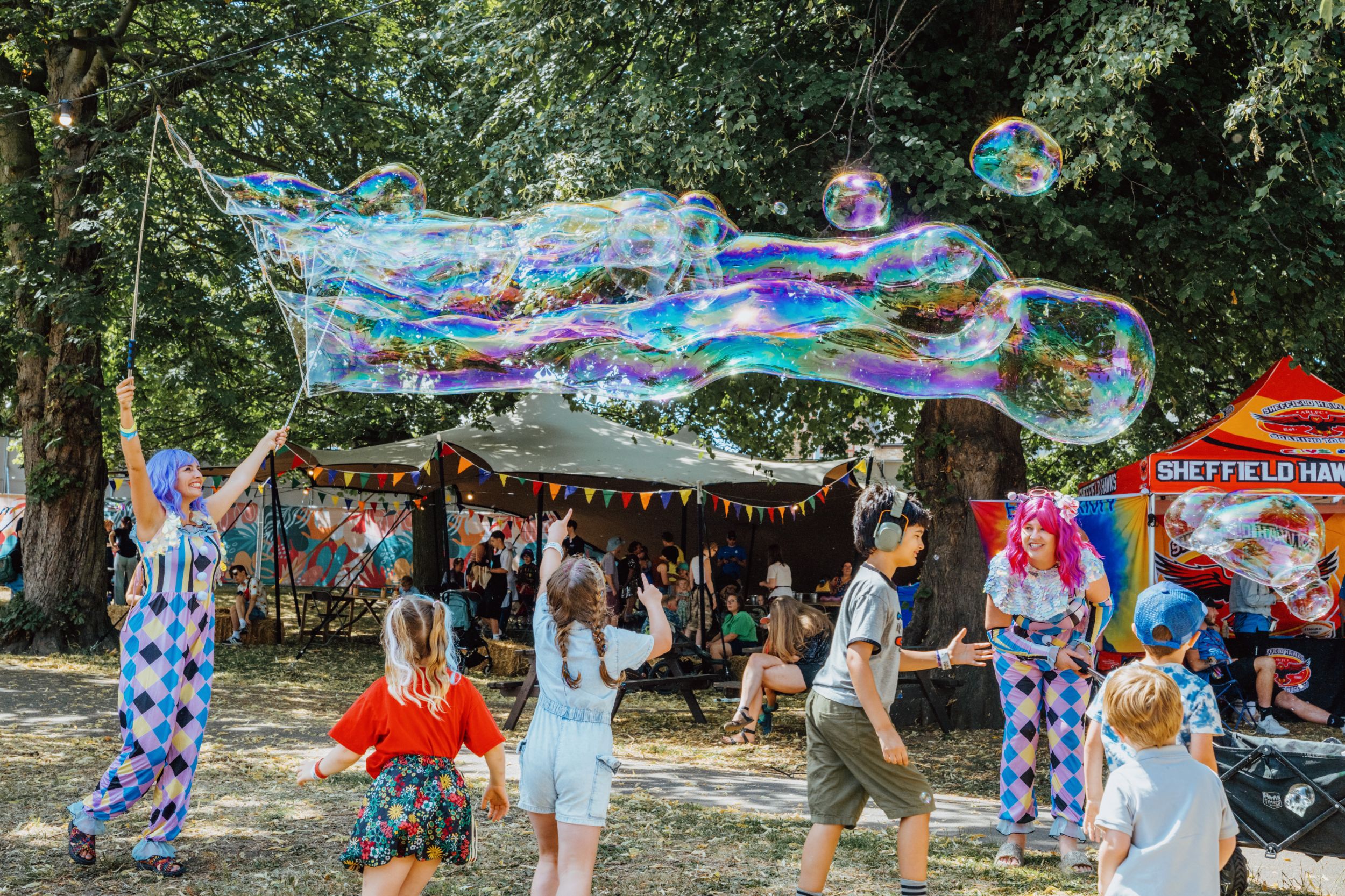 Children playing with giant bubbles at a colourful outdoor festival