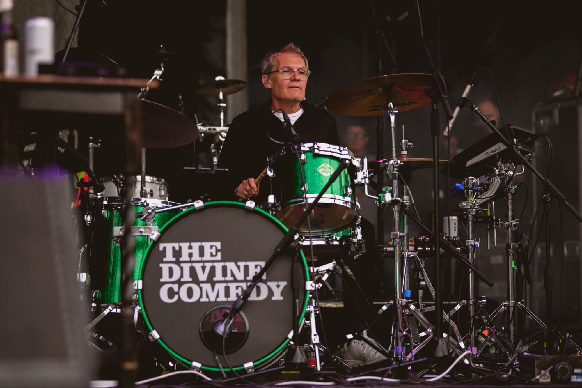 Drummer performing on stage with green drum kit