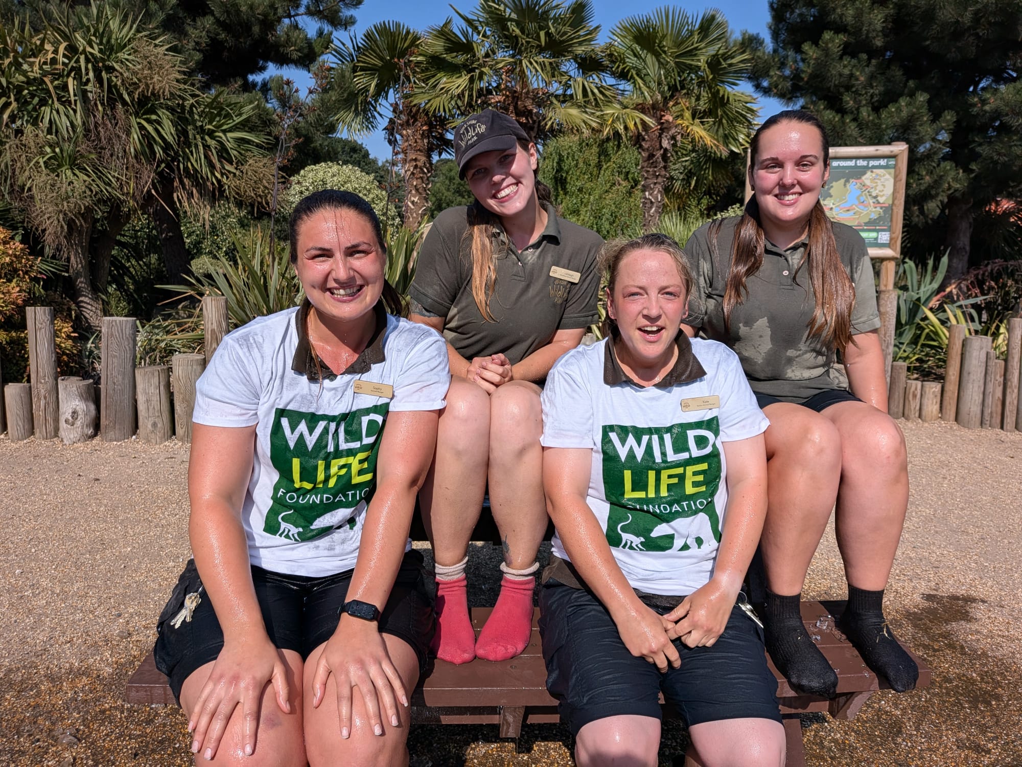 Four smiling women in wildlife park uniforms sitting on a bench