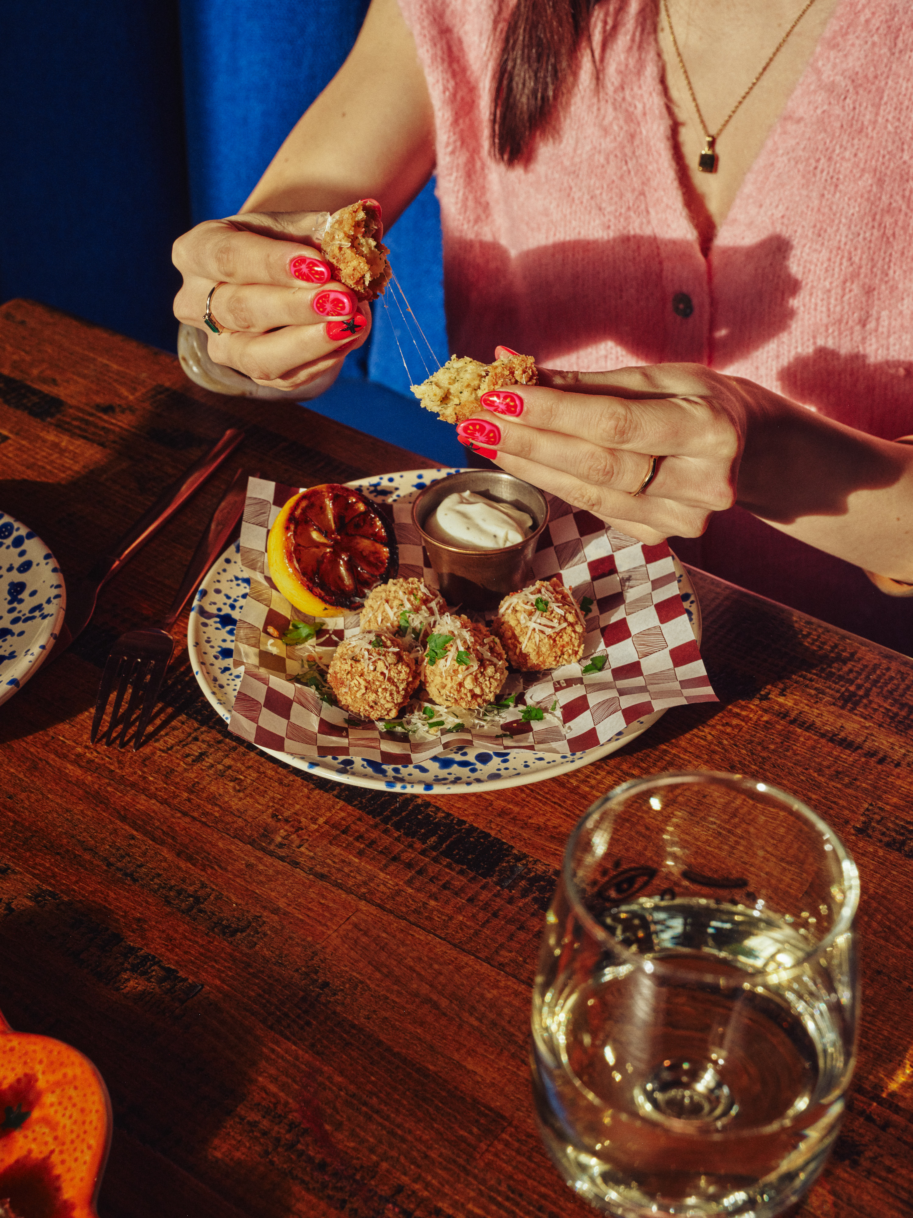 Person enjoying croquettes with dip at a rustic table