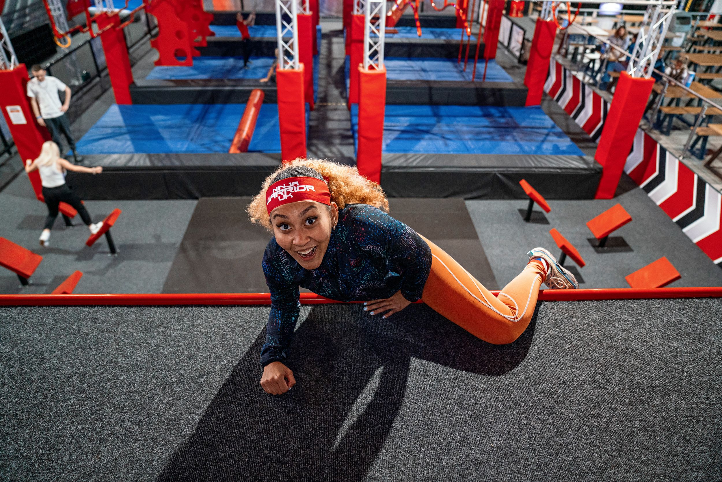 Woman climbing obstacle in indoor adventure park with red beams