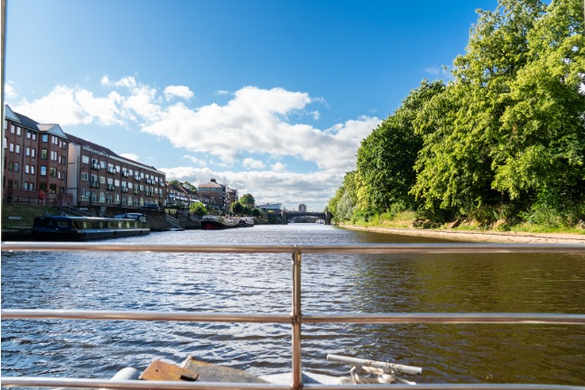 View of River Ouse with riverside buildings and lush trees