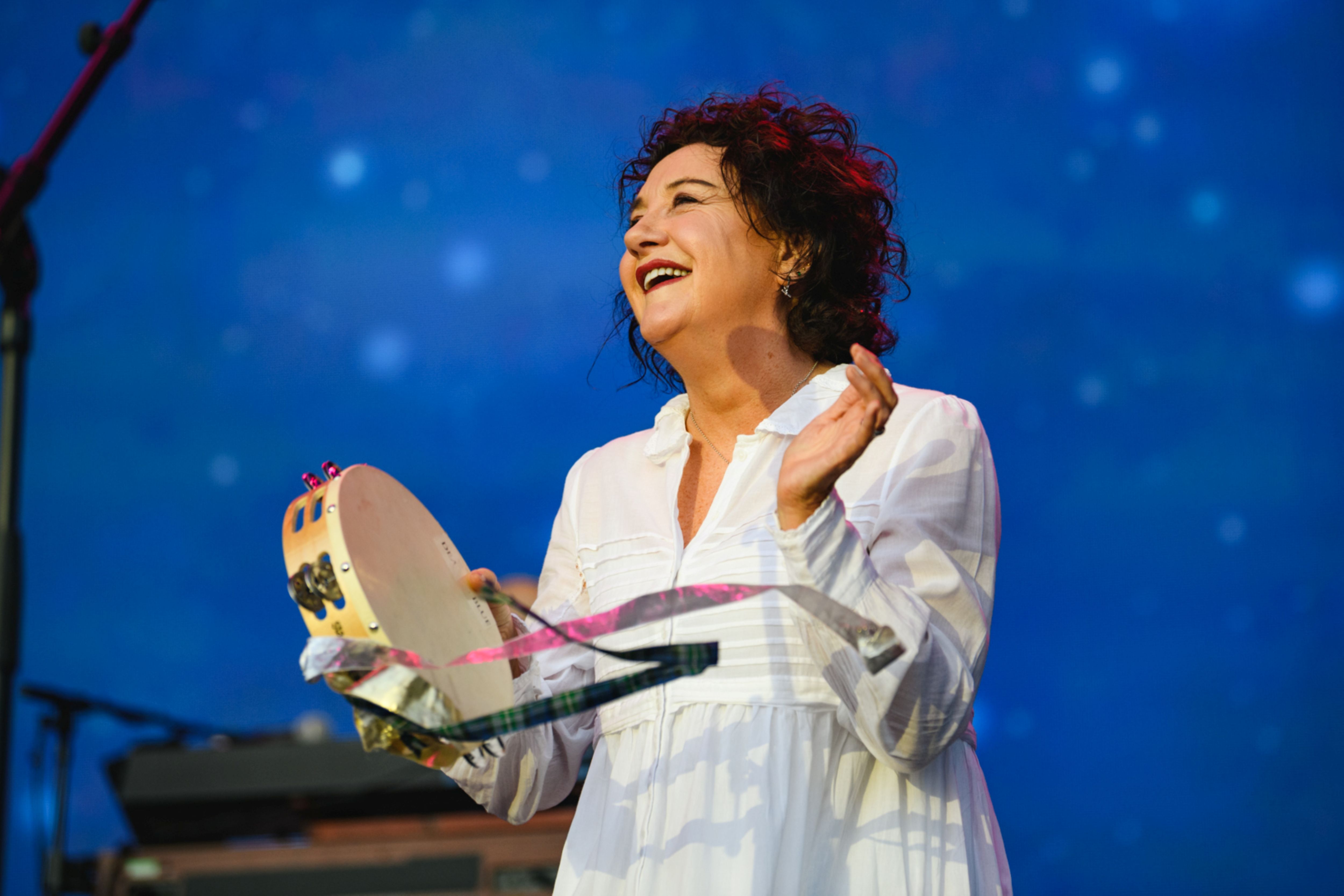 Woman in white dress playing tambourine under starry sky