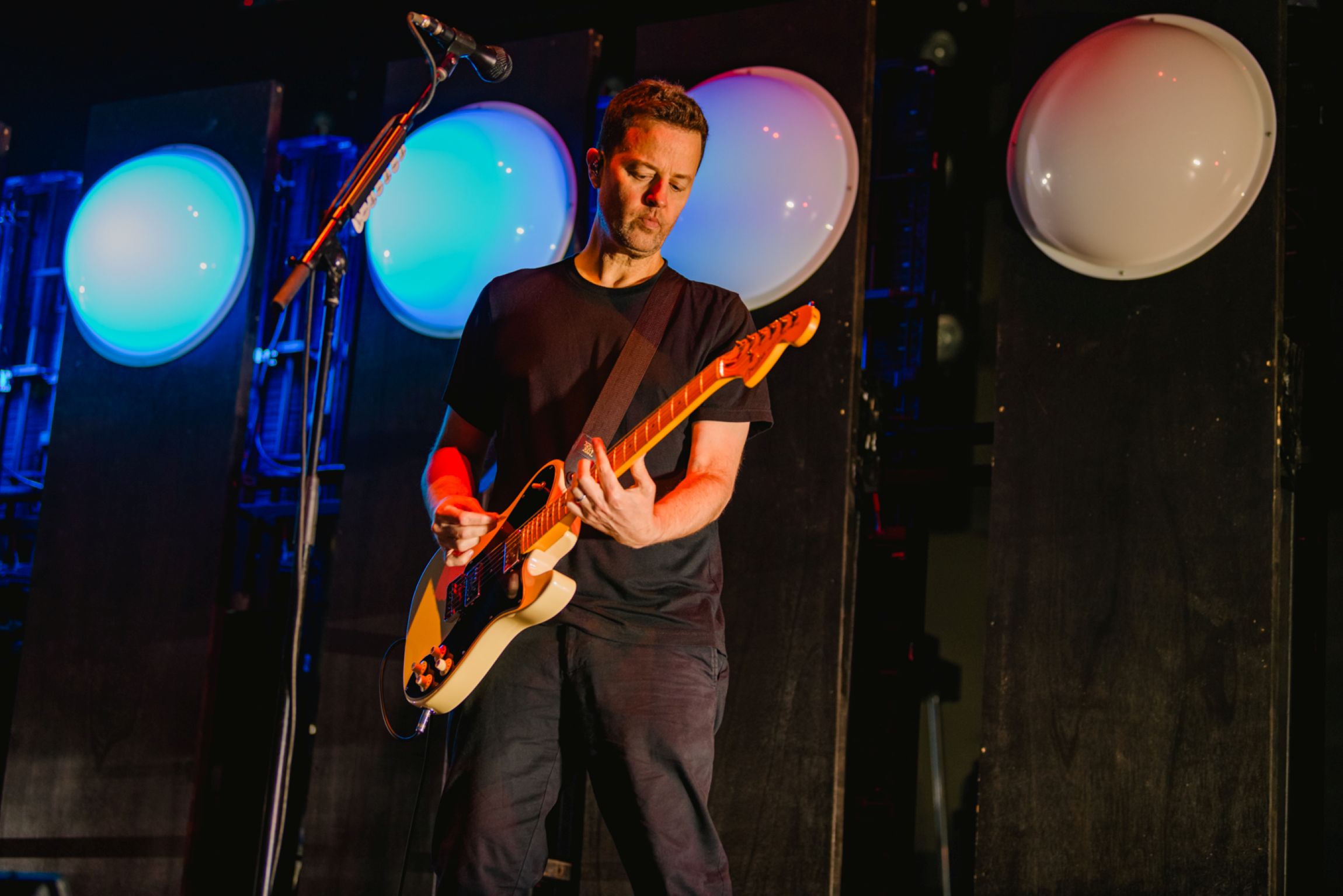 Musician playing electric guitar on stage with colourful lights