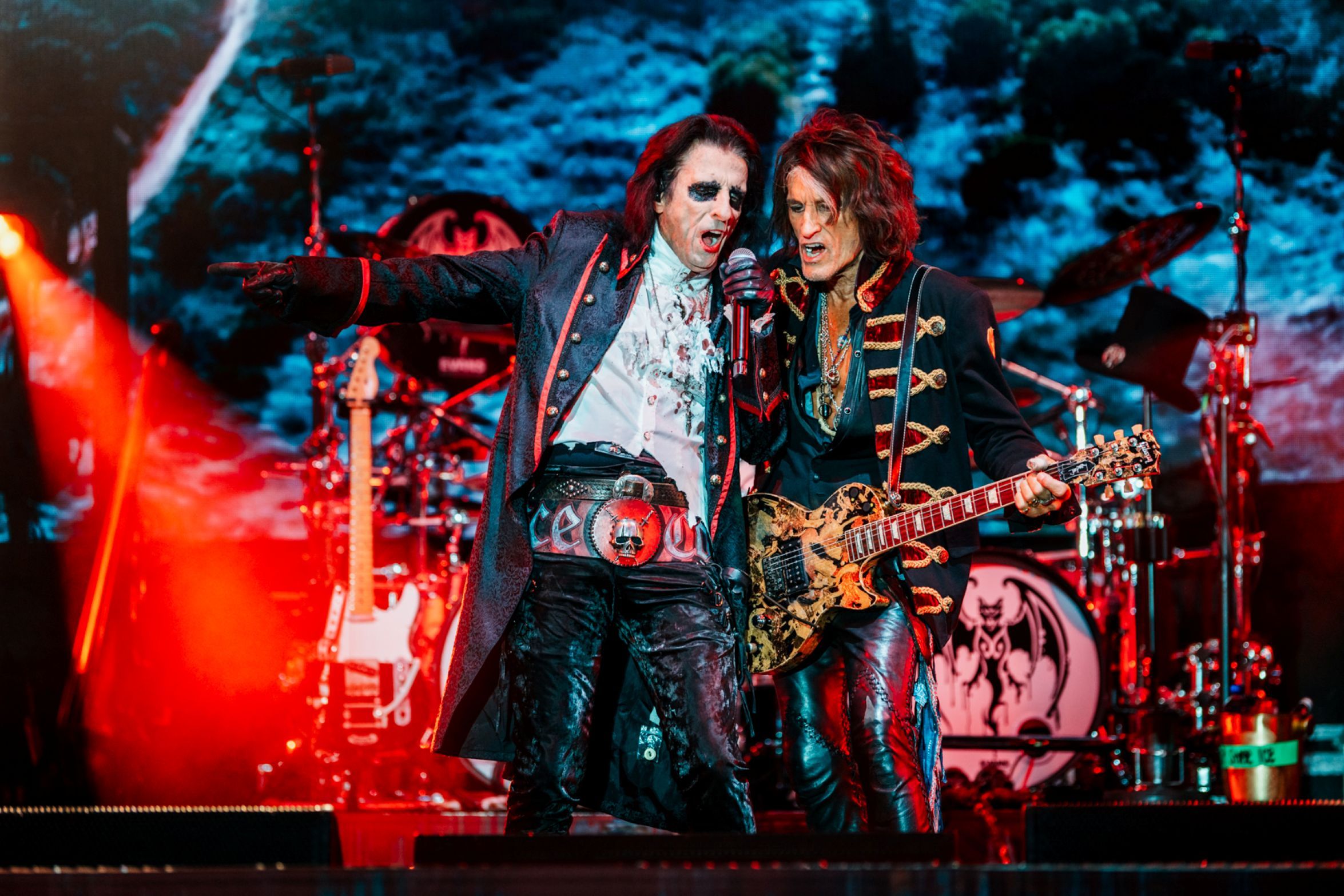 Two rock musicians performing on stage with guitars and vibrant lighting