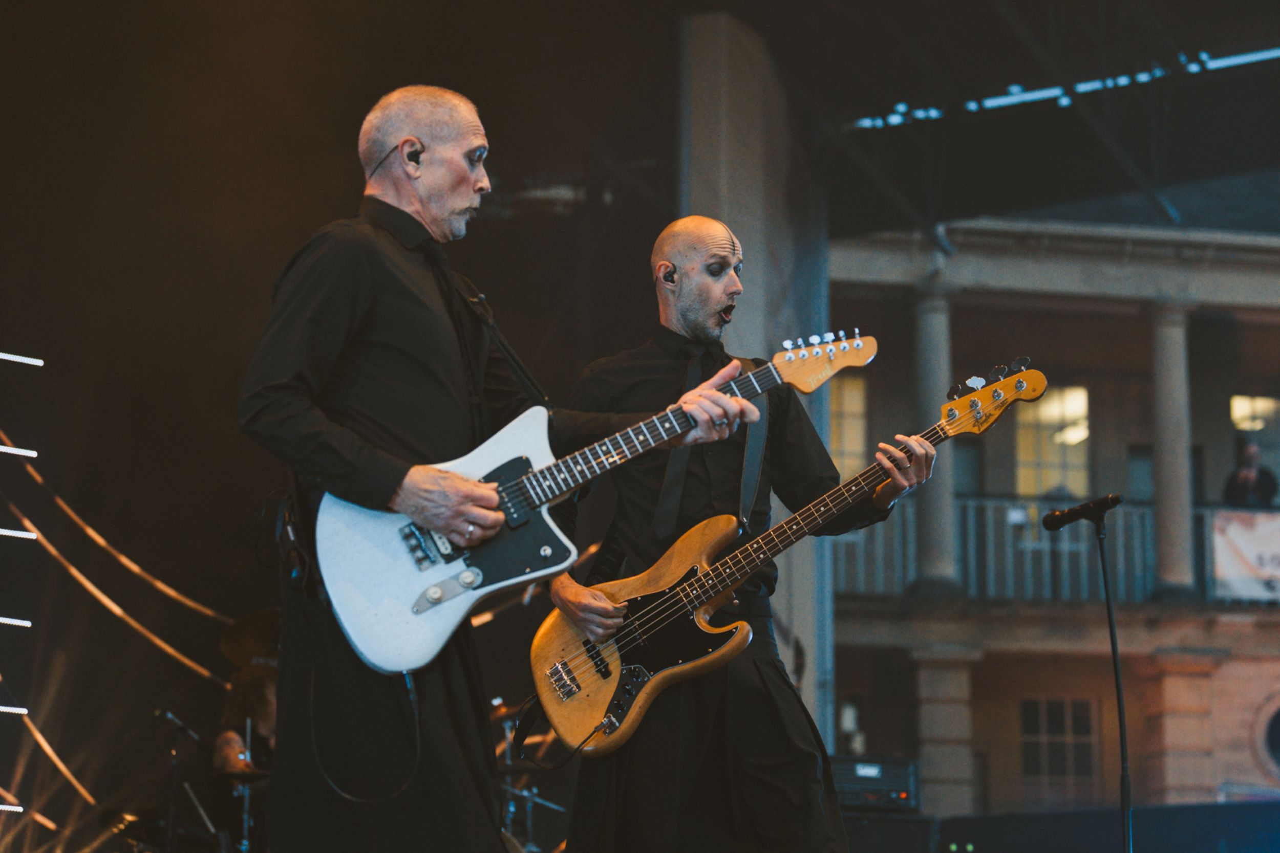 Two musicians playing guitars on stage at outdoor concert