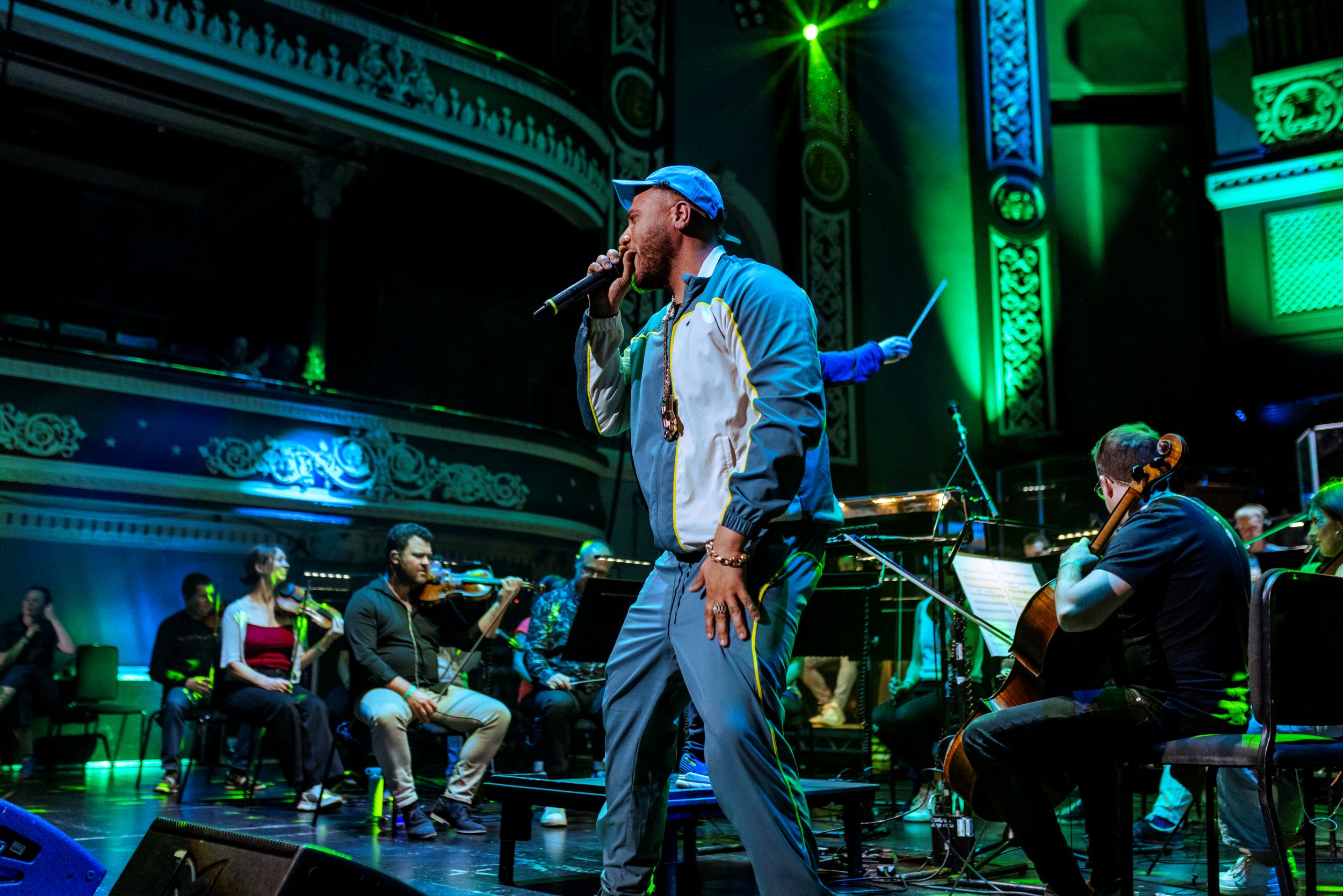 Musician performing on stage with orchestra in ornate venue