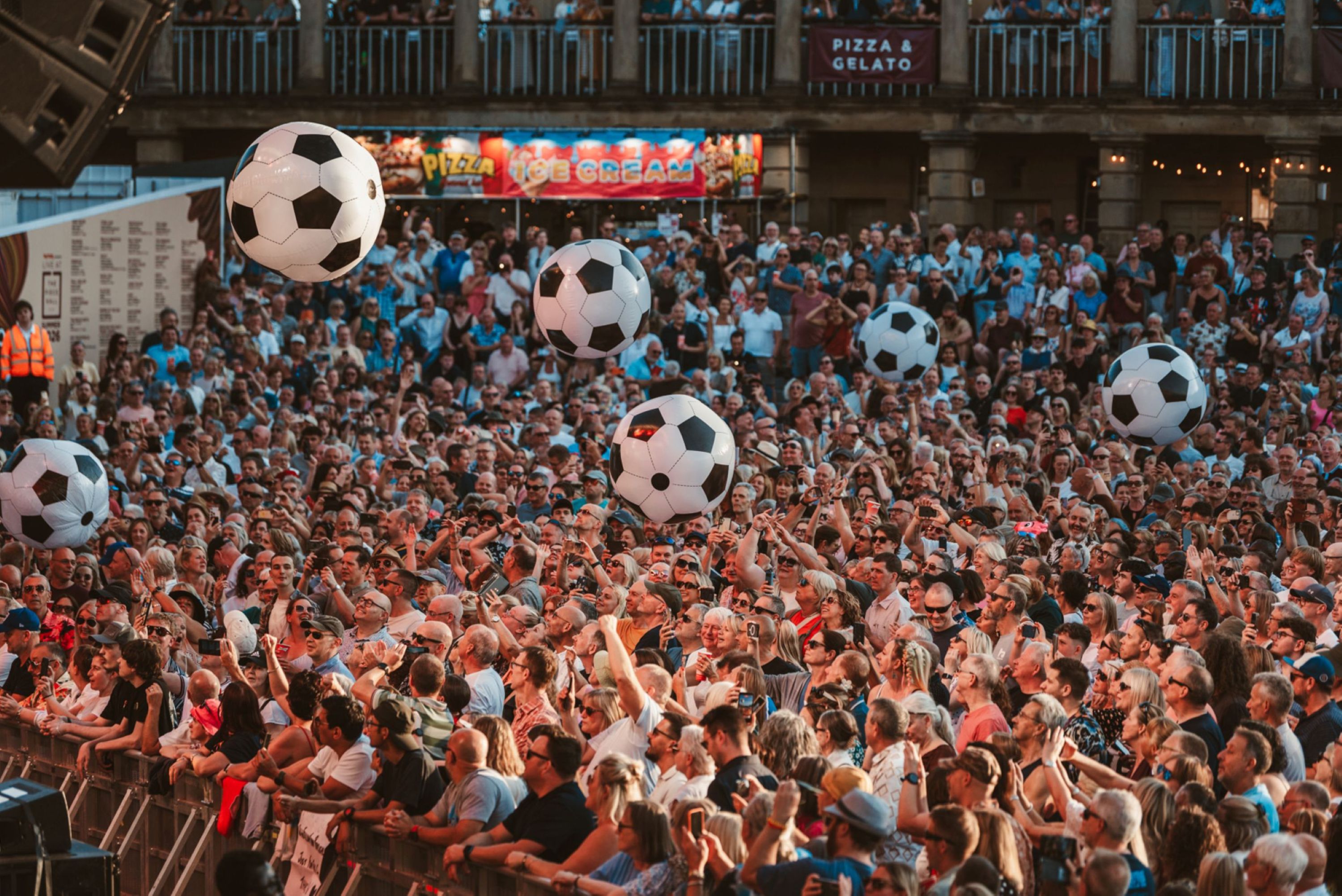 Crowd at outdoor festival with large inflatable soccer balls