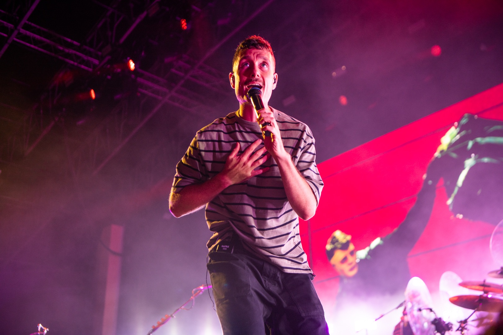 Male singer in striped shirt performing on vibrant stage
