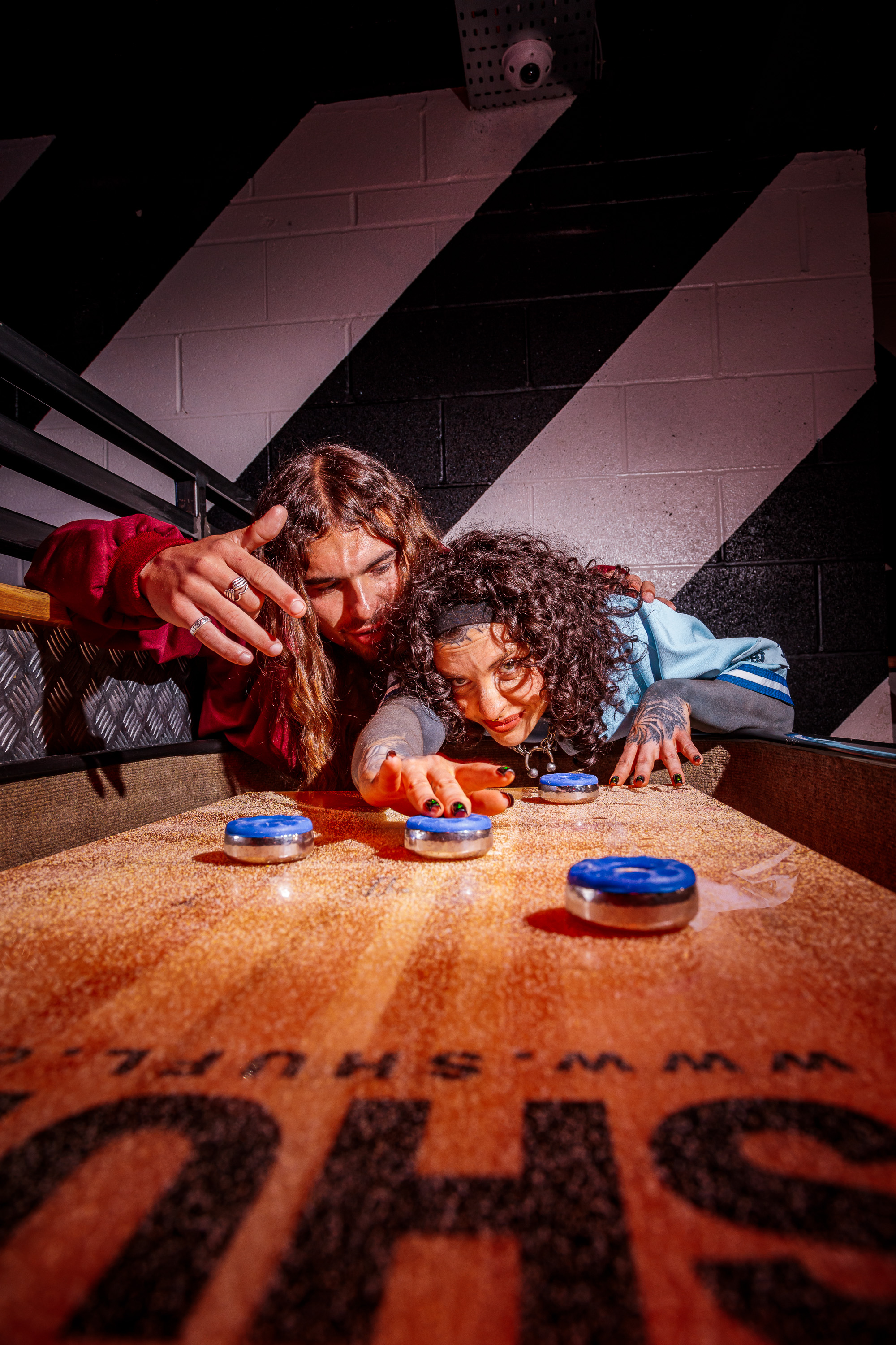 Two people playing shuffleboard in an indoor game venue