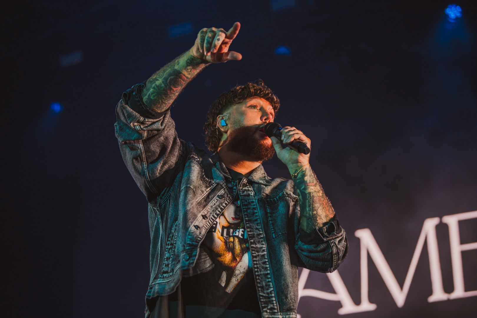 Singer performing on stage with microphone and denim jacket