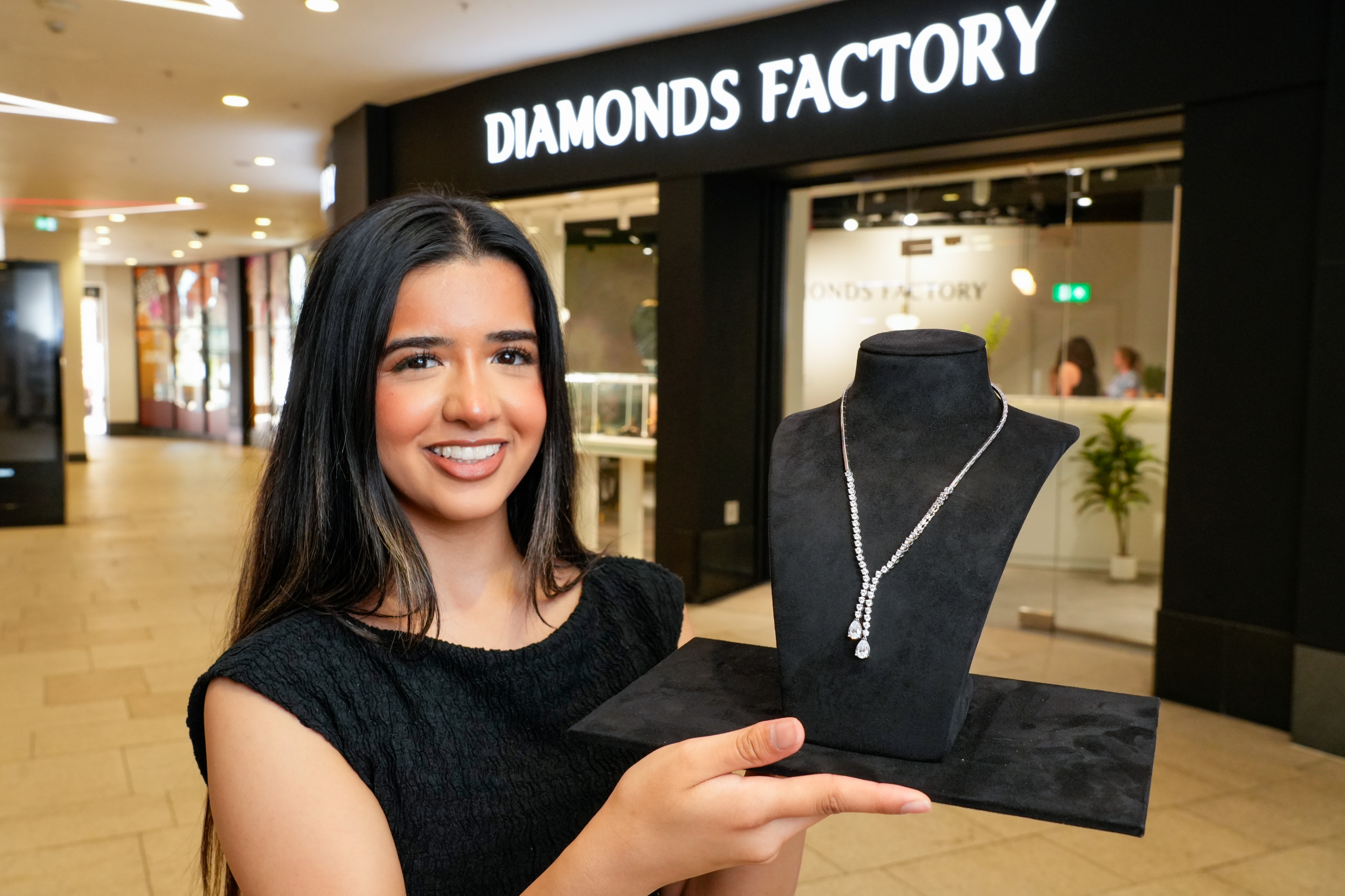 Smiling woman presenting a diamond necklace in jewellery shop