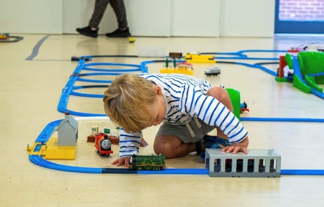 Young child playing with toy train set on wooden floor