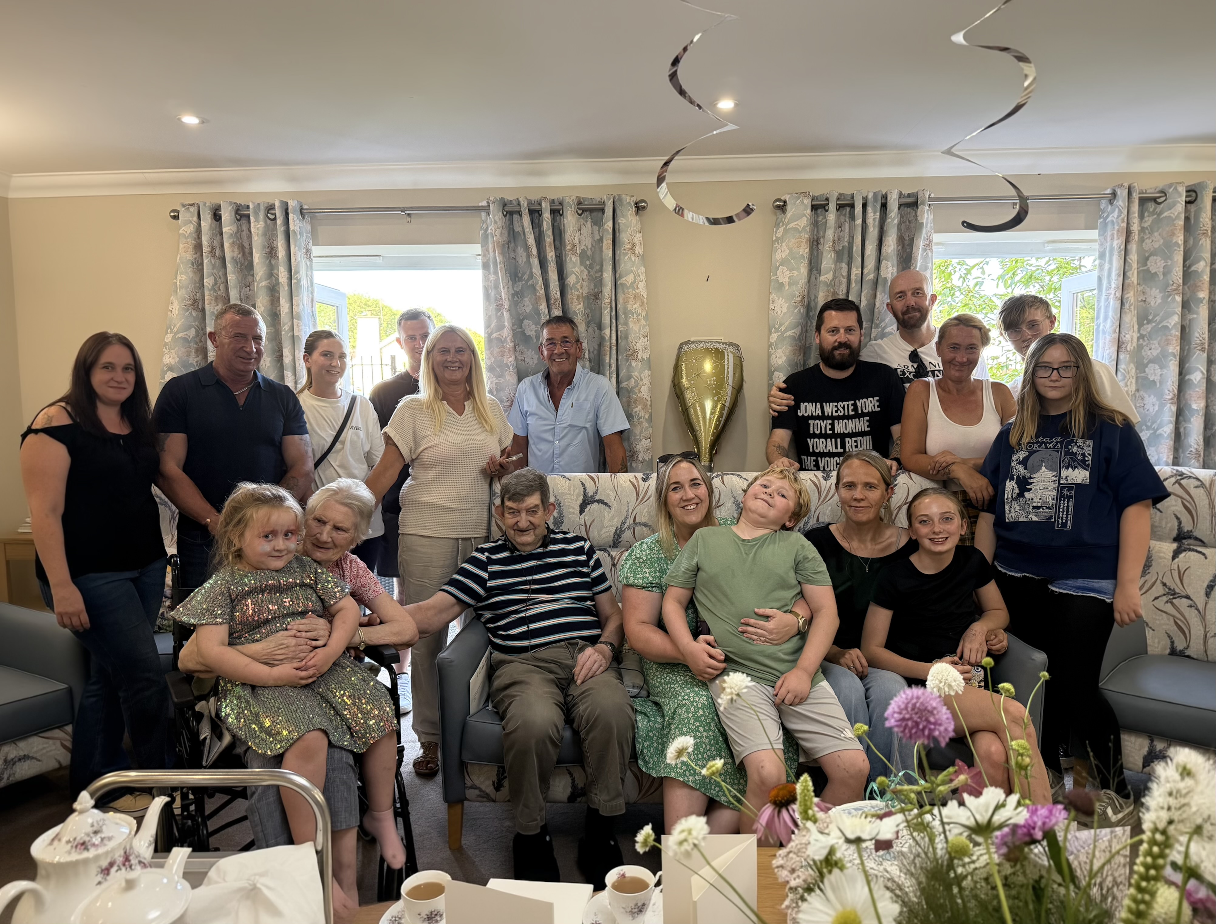 Group of people in a cosy living room with balloons and flowers