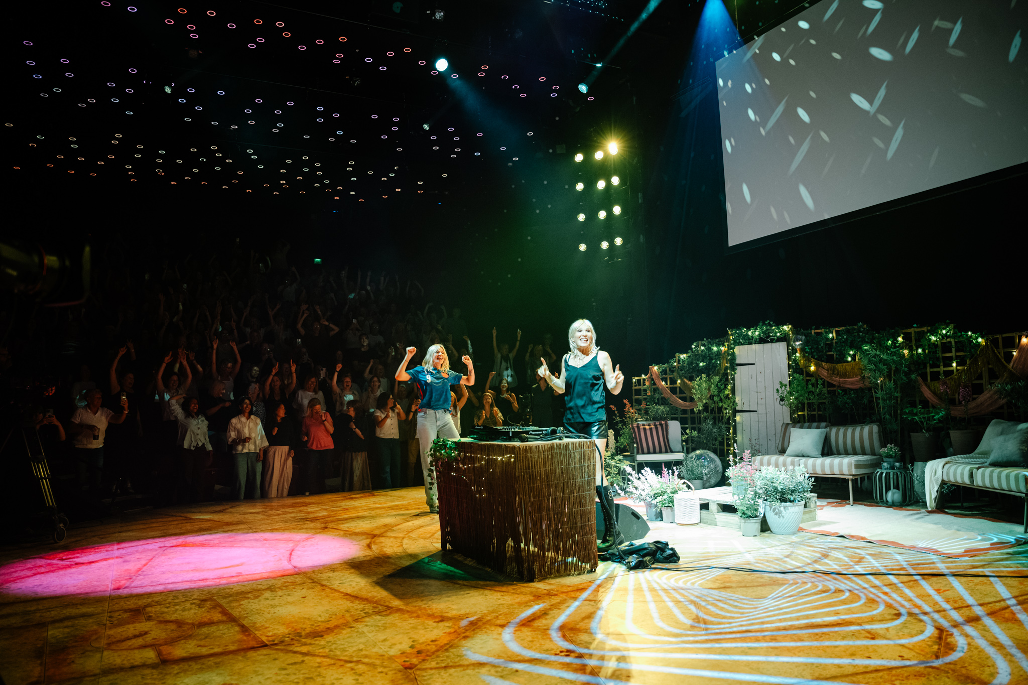 Two performers on stage with audience clapping in theater