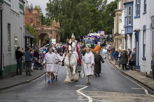 Historical parade with costumed figures and horse on village street