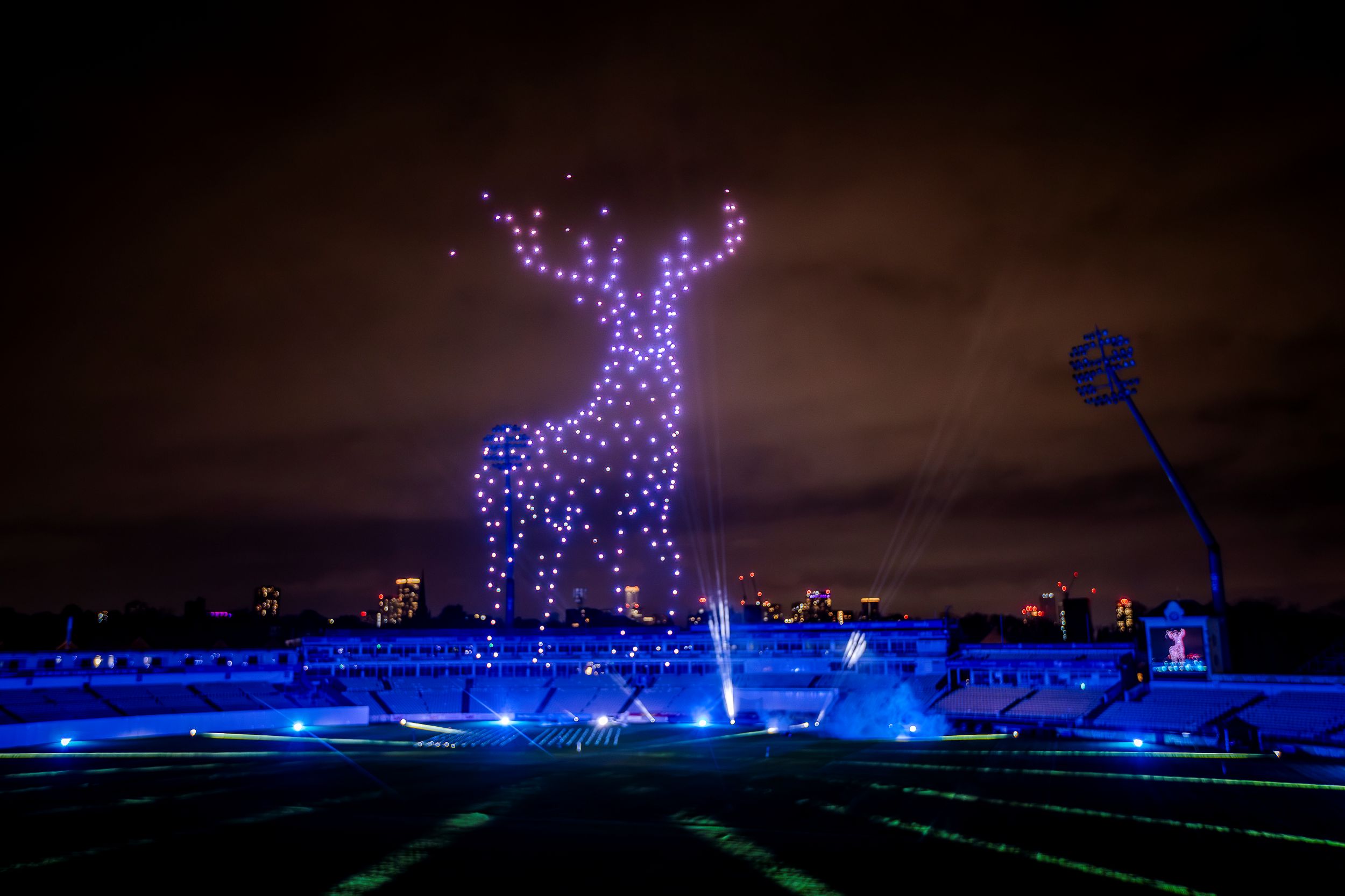 Illuminated deer shape formed by drones over a stadium at night