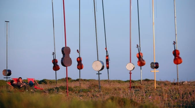 Art installation of musical instruments on poles in a field