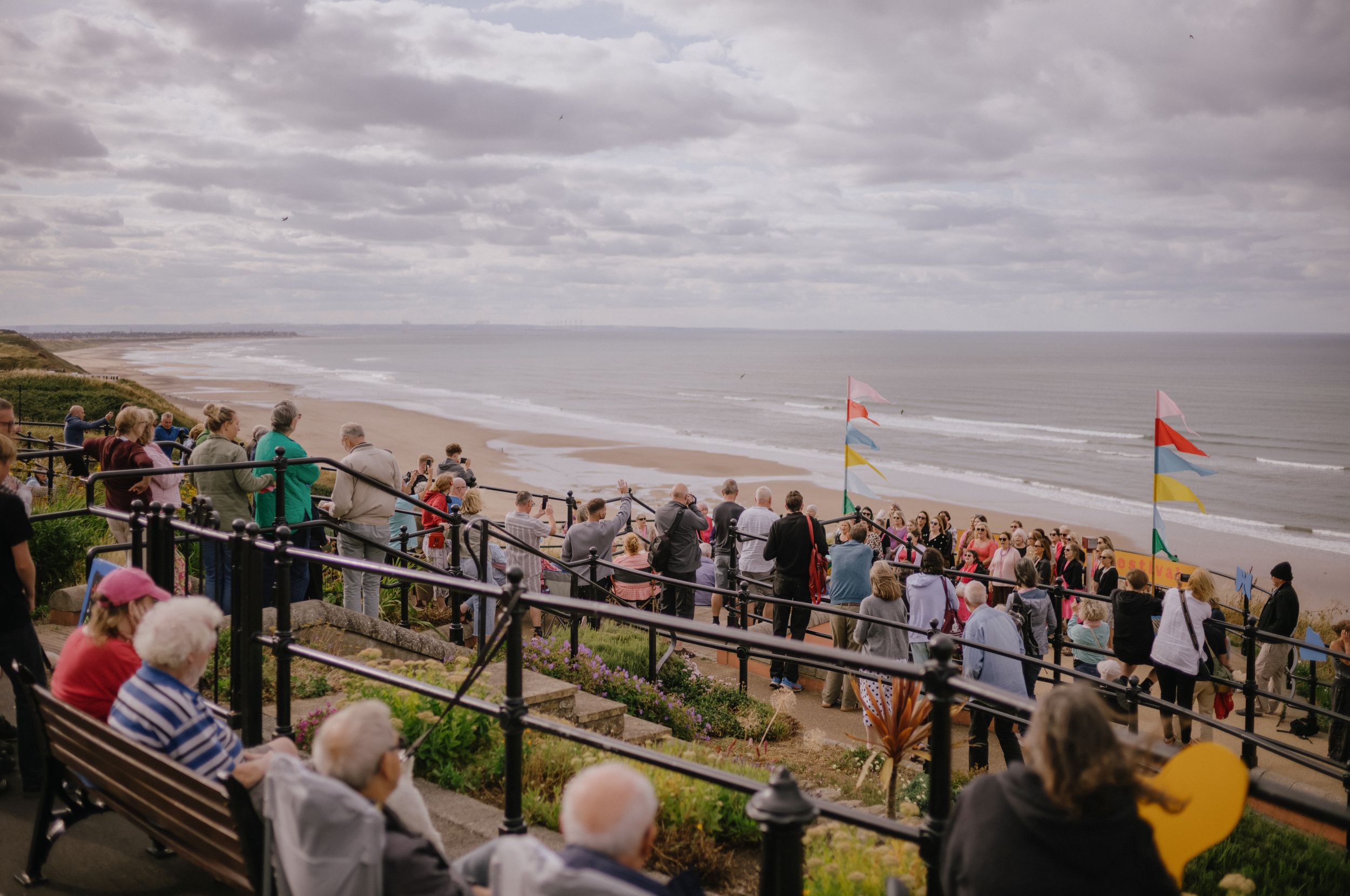 Crowd enjoying seaside view from cliff top with flags in Yorkshire