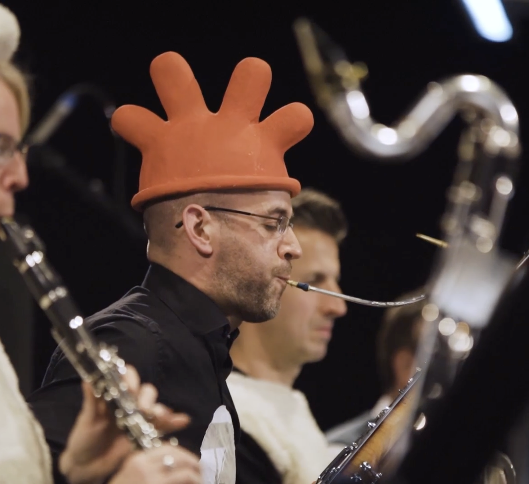 Musician in quirky orange hat playing clarinet on stage
