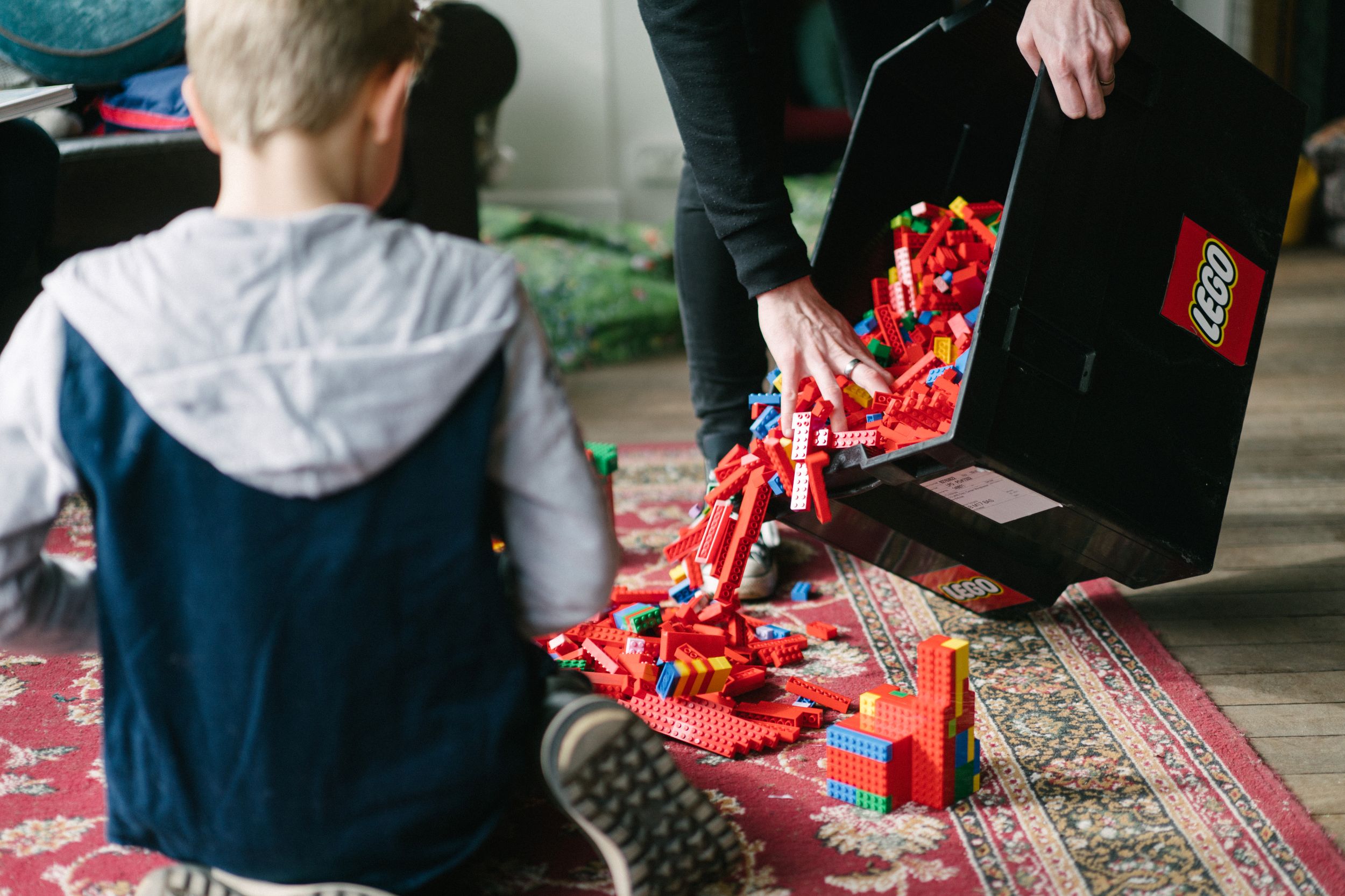 Child playing with colourful building blocks on a patterned rug