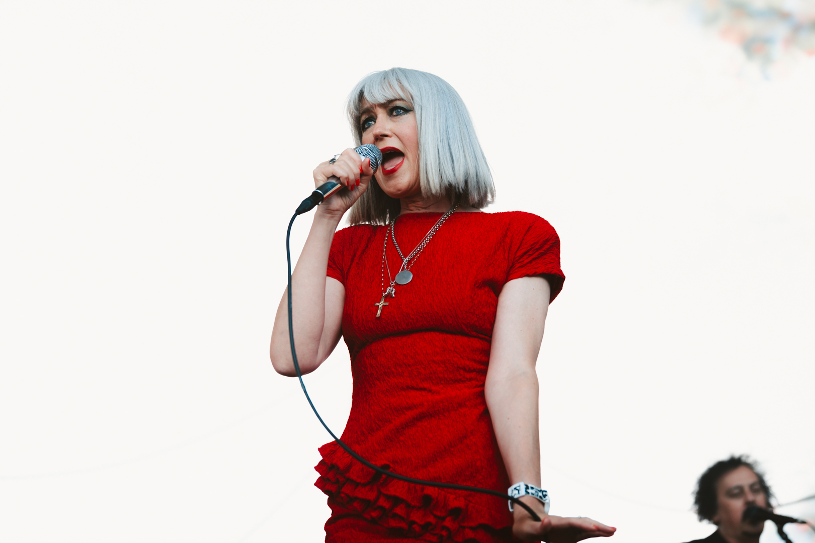 Woman in red dress singing passionately on stage with a microphone