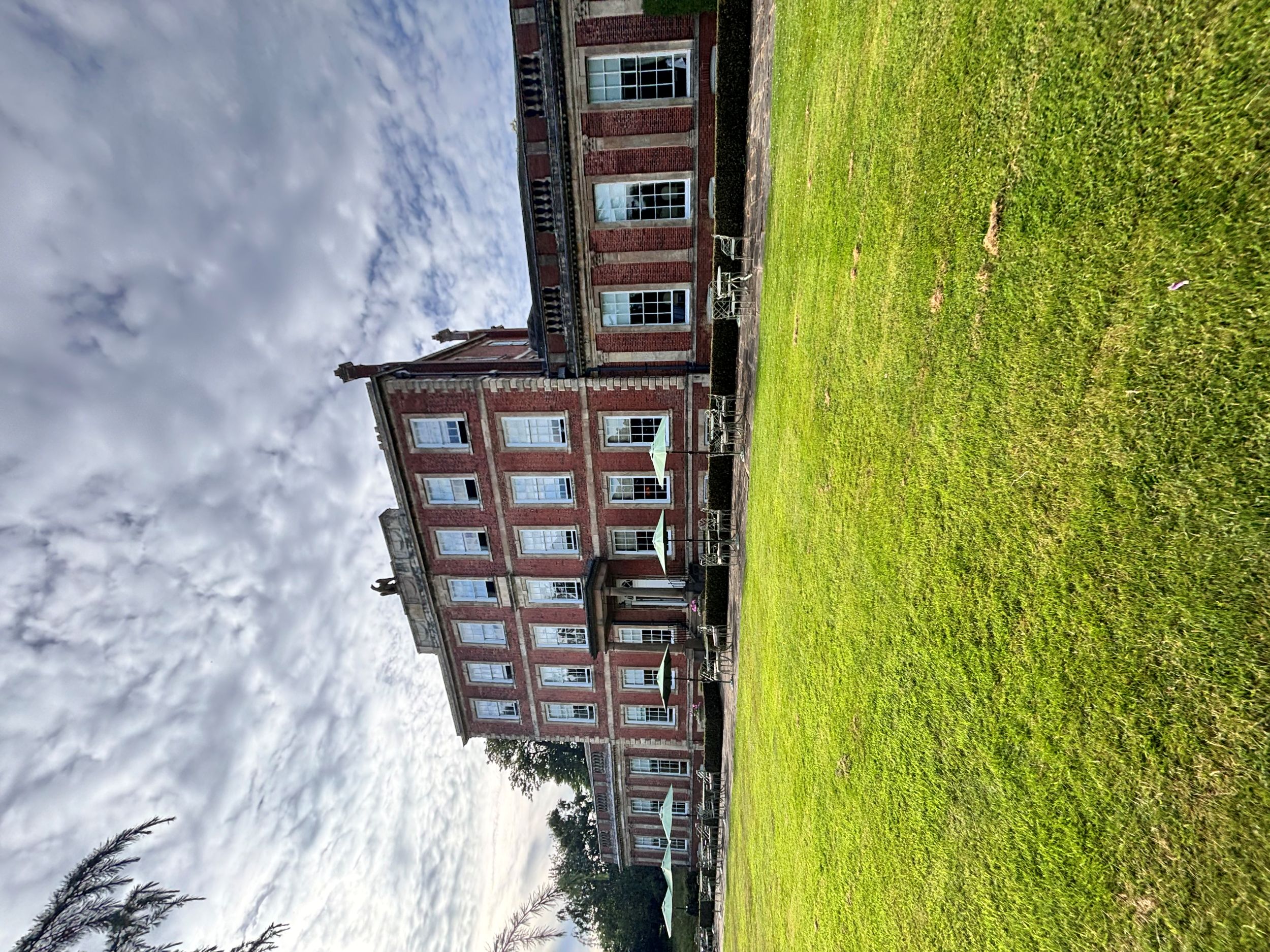 Historic red brick mansion with white columns and green lawn