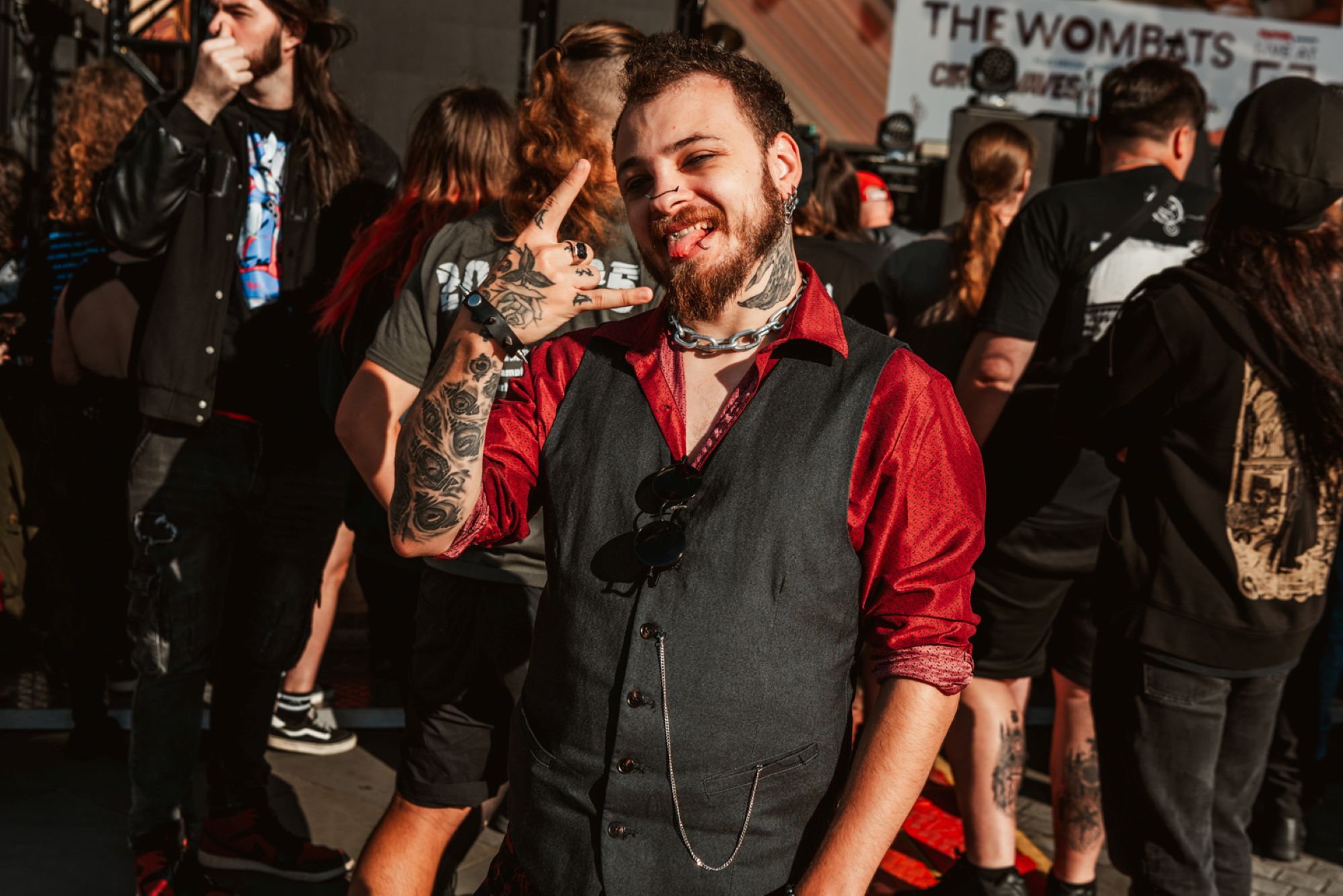 Smiling man with tattoos and red shirt at outdoor music festival