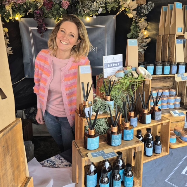 Woman smiling at wooden stall with scented products