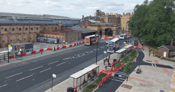 Historic York railway station with buses and red barriers
