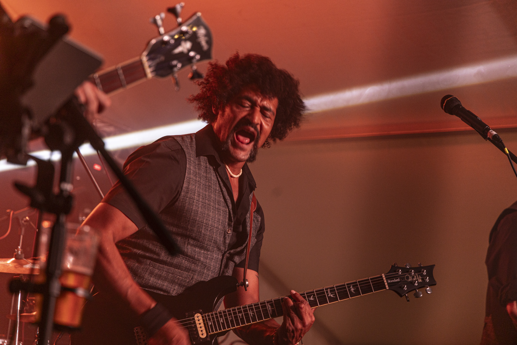 Guitarist performing energetically under red stage lights