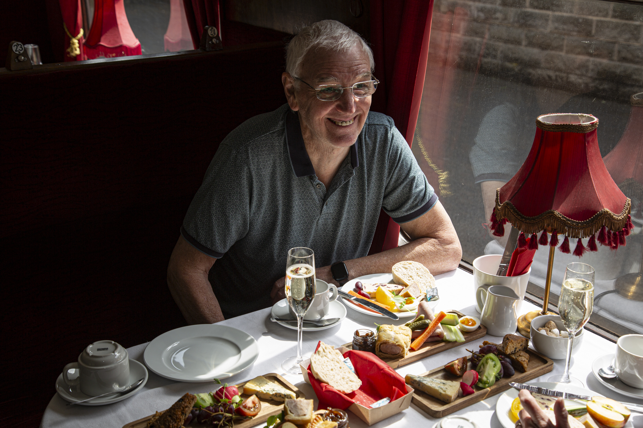 Smiling man enjoying afternoon tea with sandwiches and scones