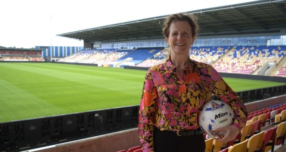 Smiling person holding soccer ball in colorful stadium