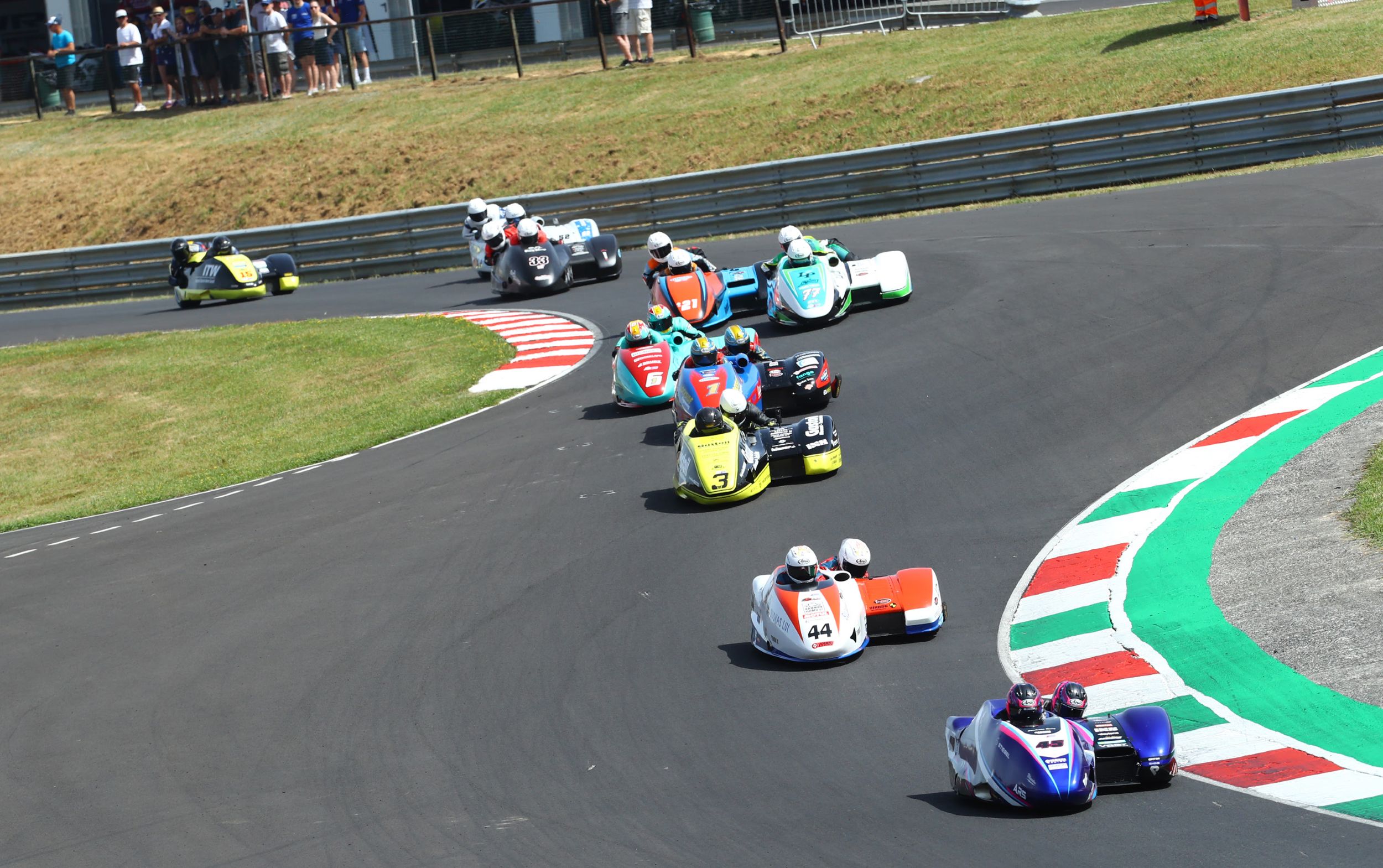Motorcycle sidecars racing on a winding track with spectators