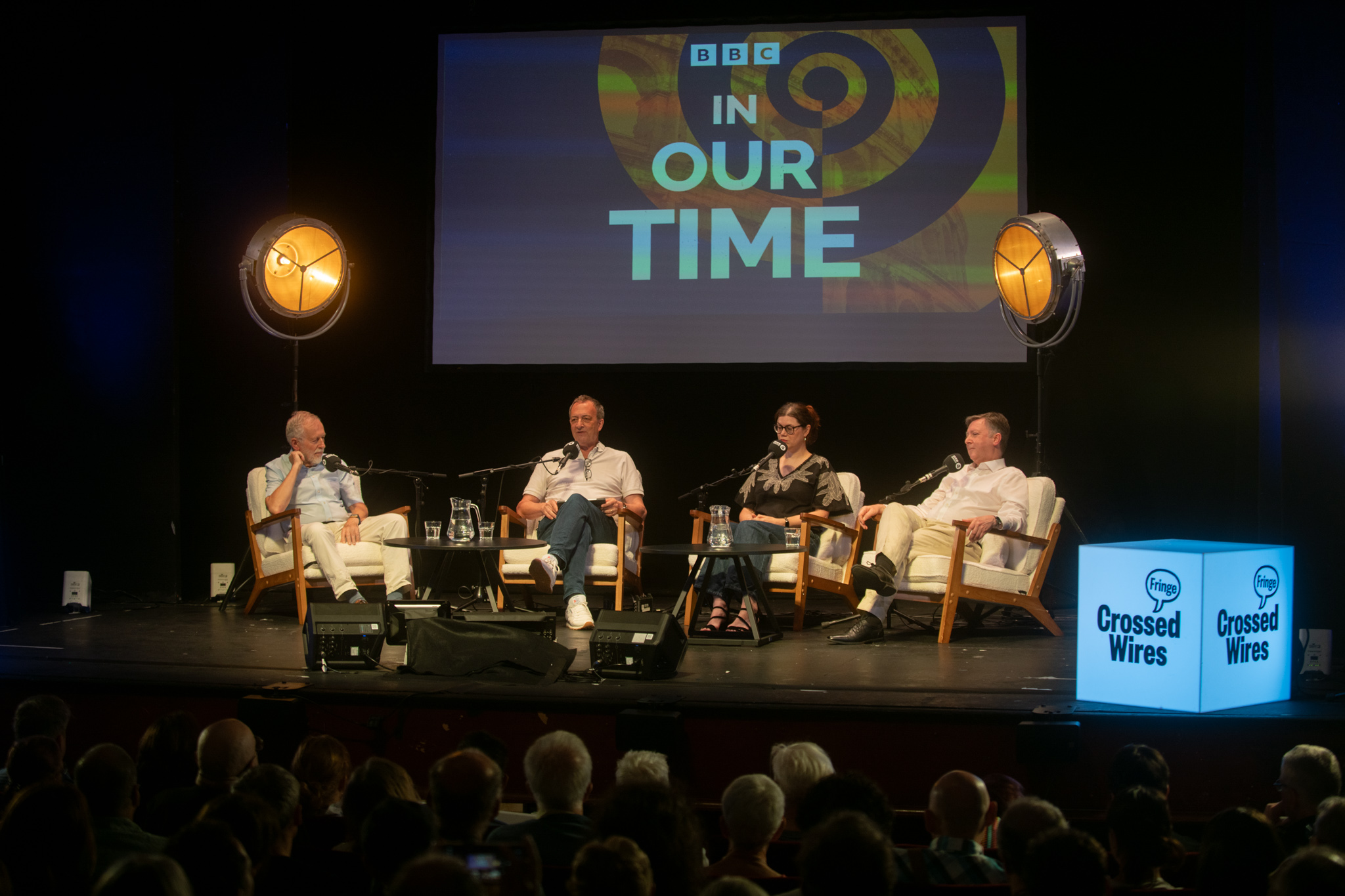 Panel discussion on stage with four speakers under studio lights