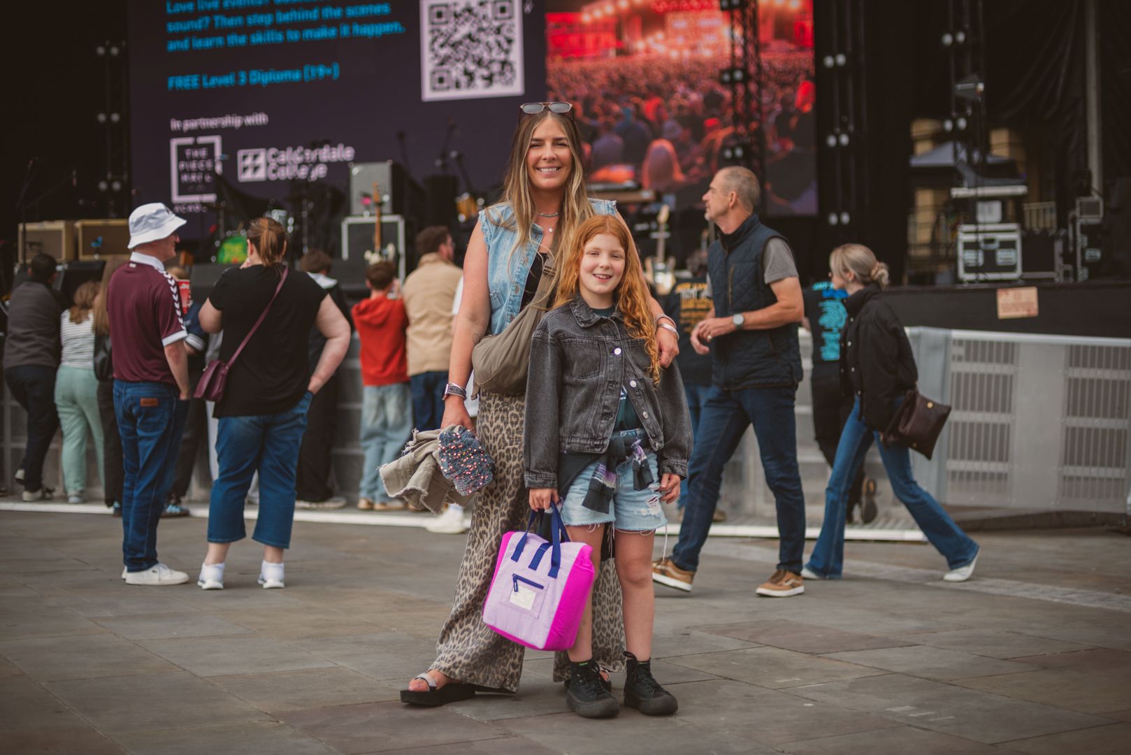 Smiling woman and girl in casual outfits at outdoor festival