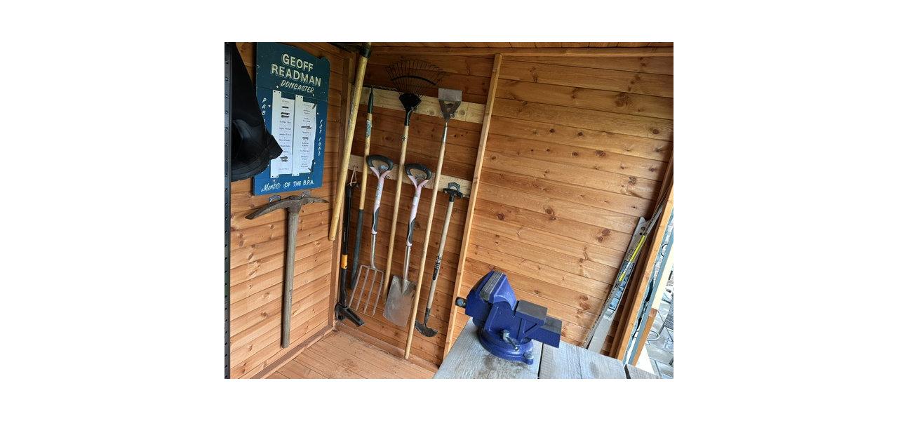 Wooden garden shed interior with tools and blue vise